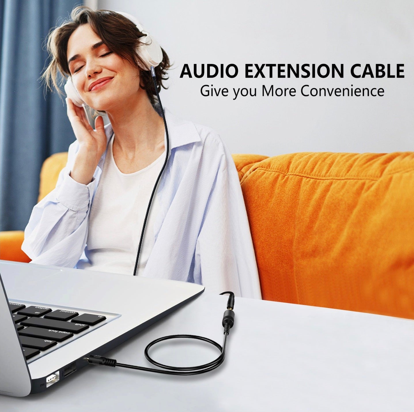 A woman sitting on a sofa with a content expression, using a black 3.5mm stereo female to female audio extension cable connected to a device on the table in front of her.