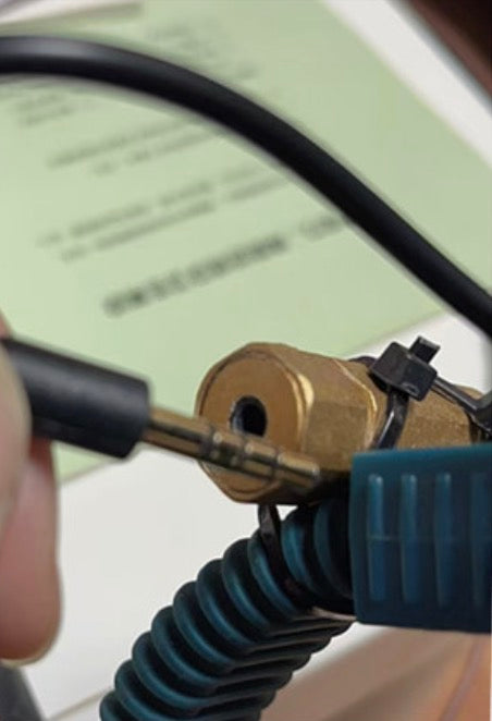 Person using a tool to work on a brass fitting with a blurred background