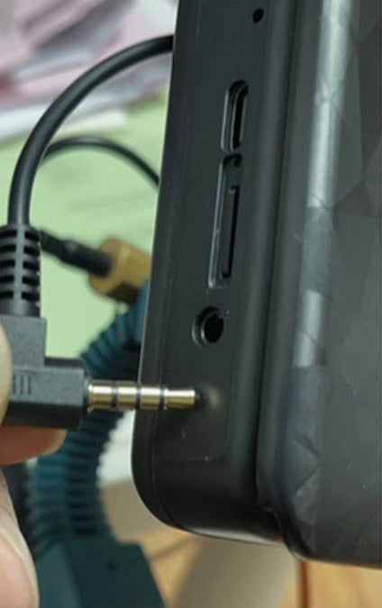 Close-up of a device with a 3.5mm jack being plugged in.