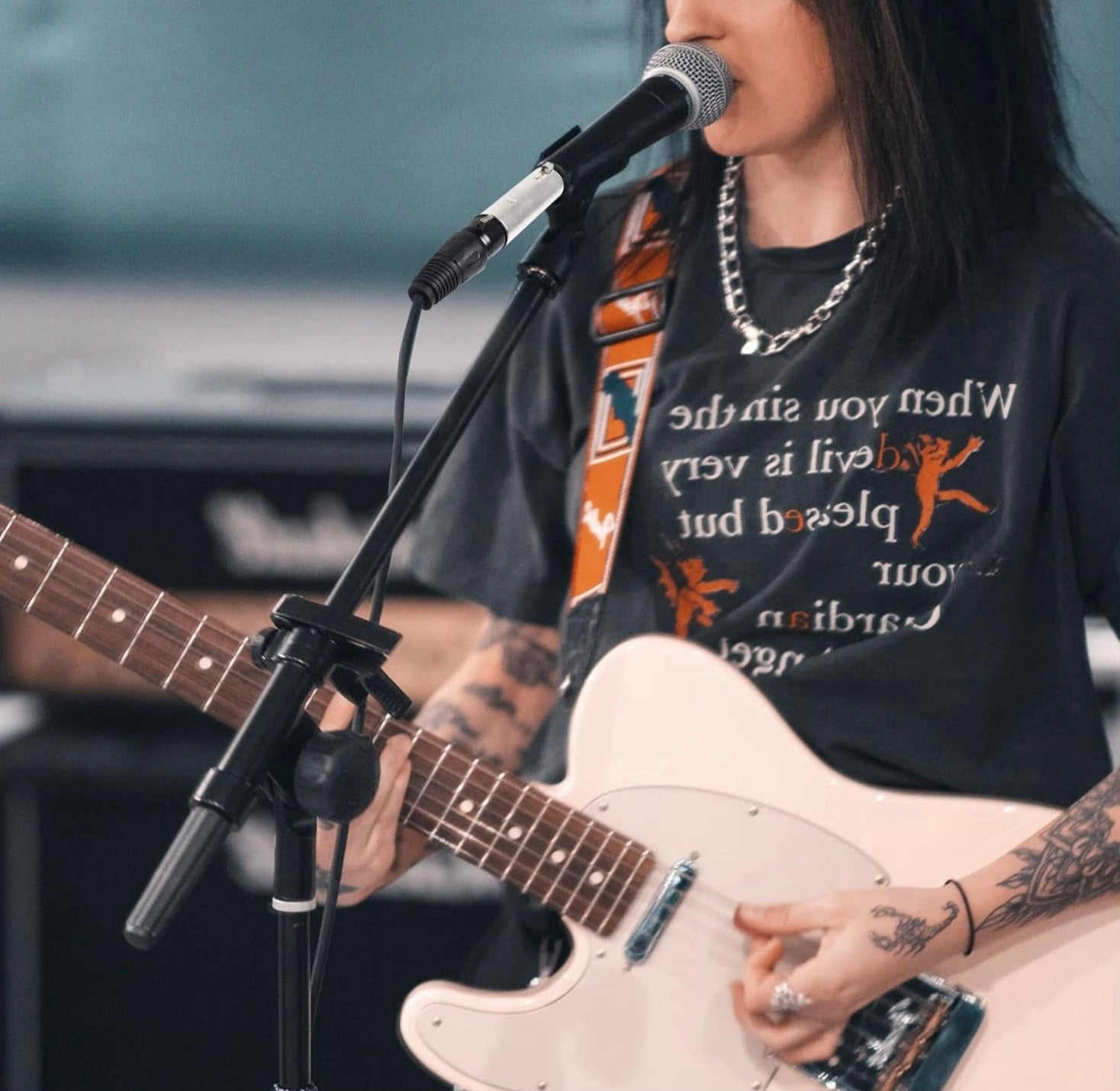 Person playing electric guitar and singing into microphone.