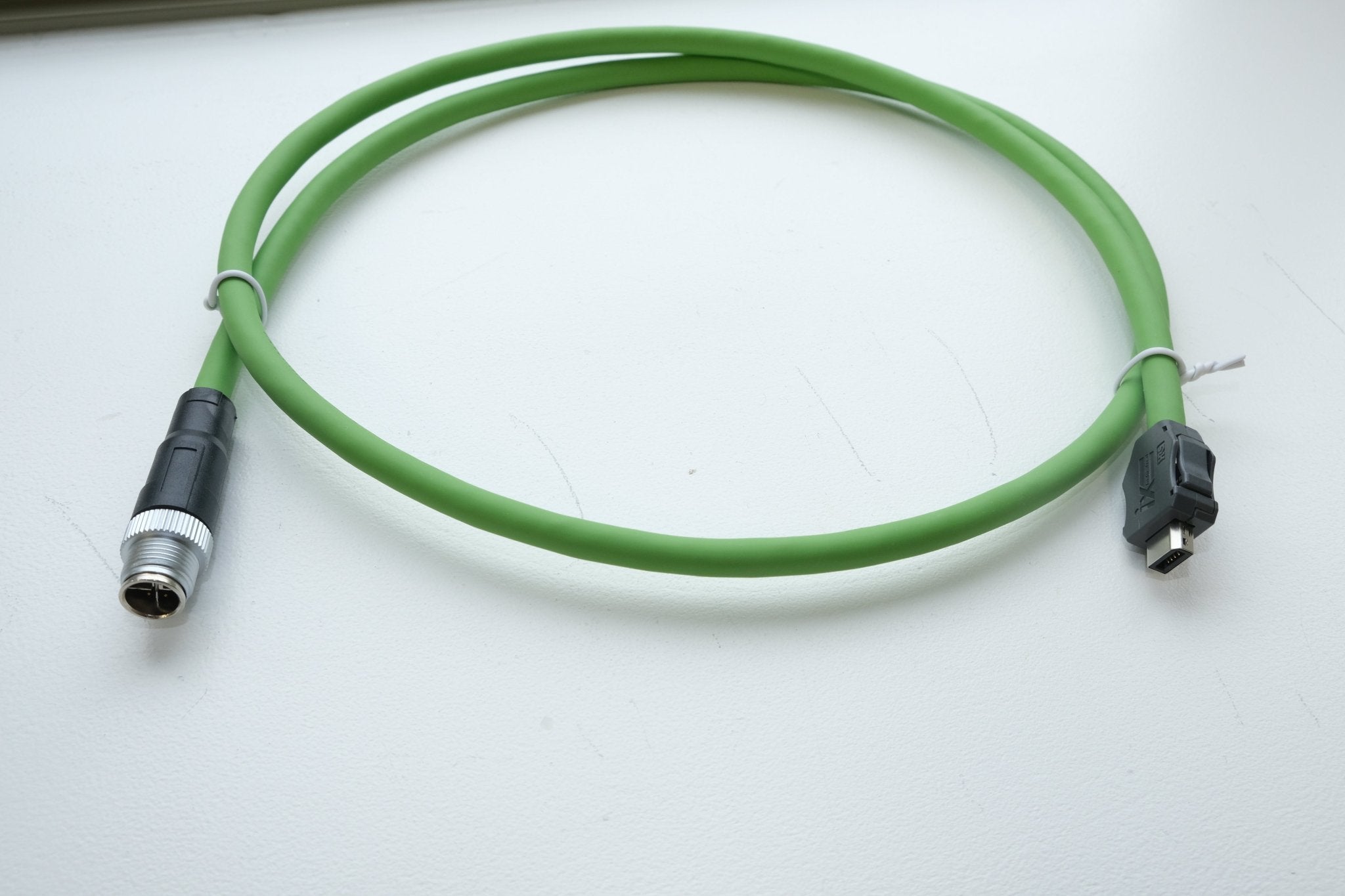 Green cable with black connectors on a white background