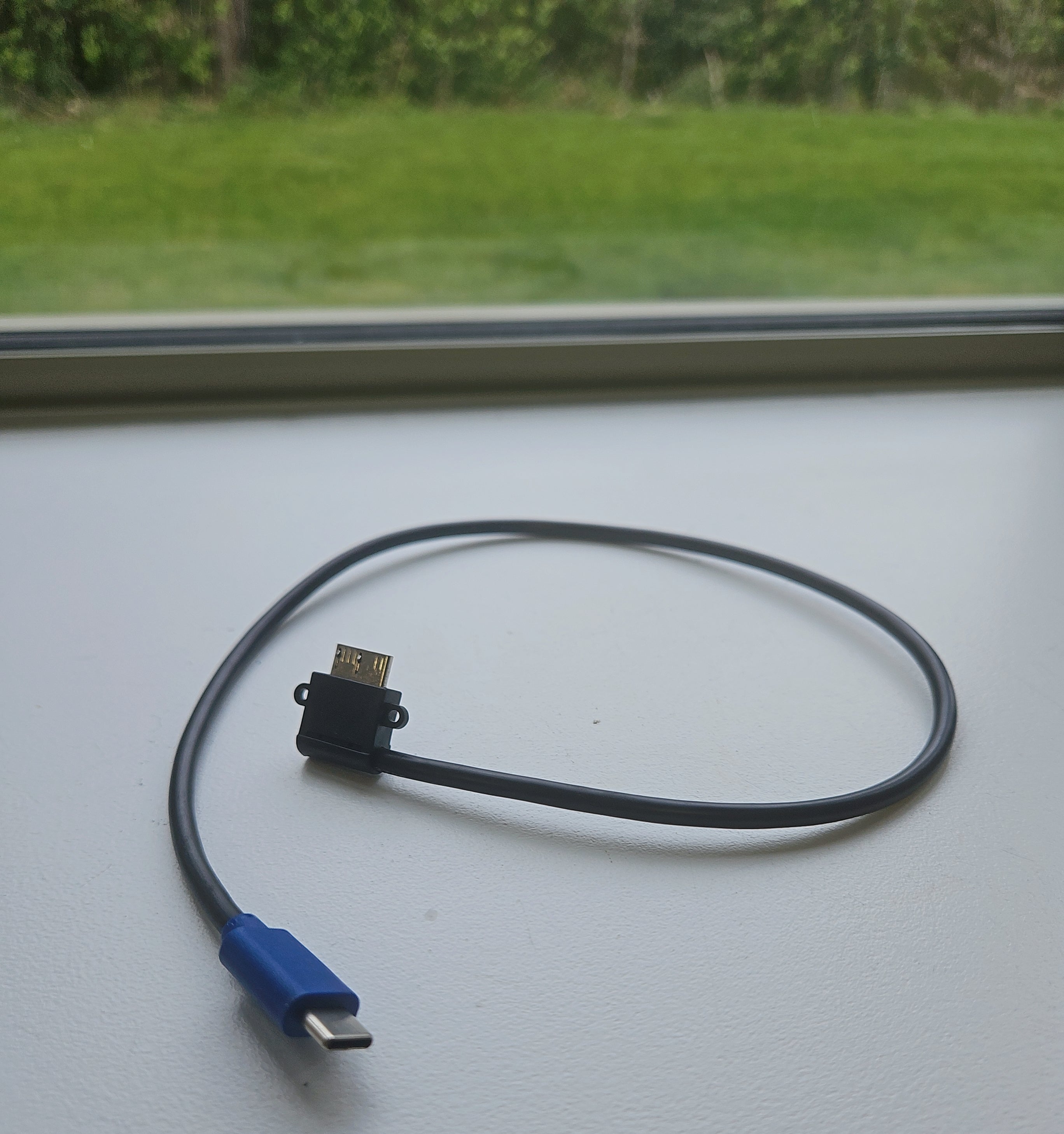 HDMI and micro USB cable on a flat surface with a window in the background