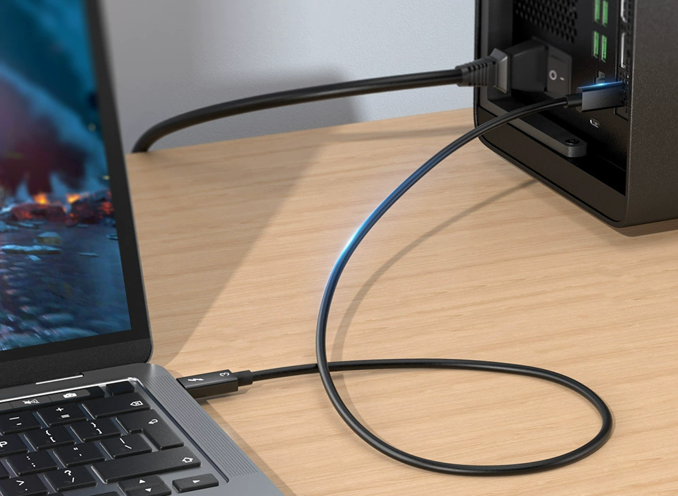 Laptop connected to a external device via a cable on a wooden desk.