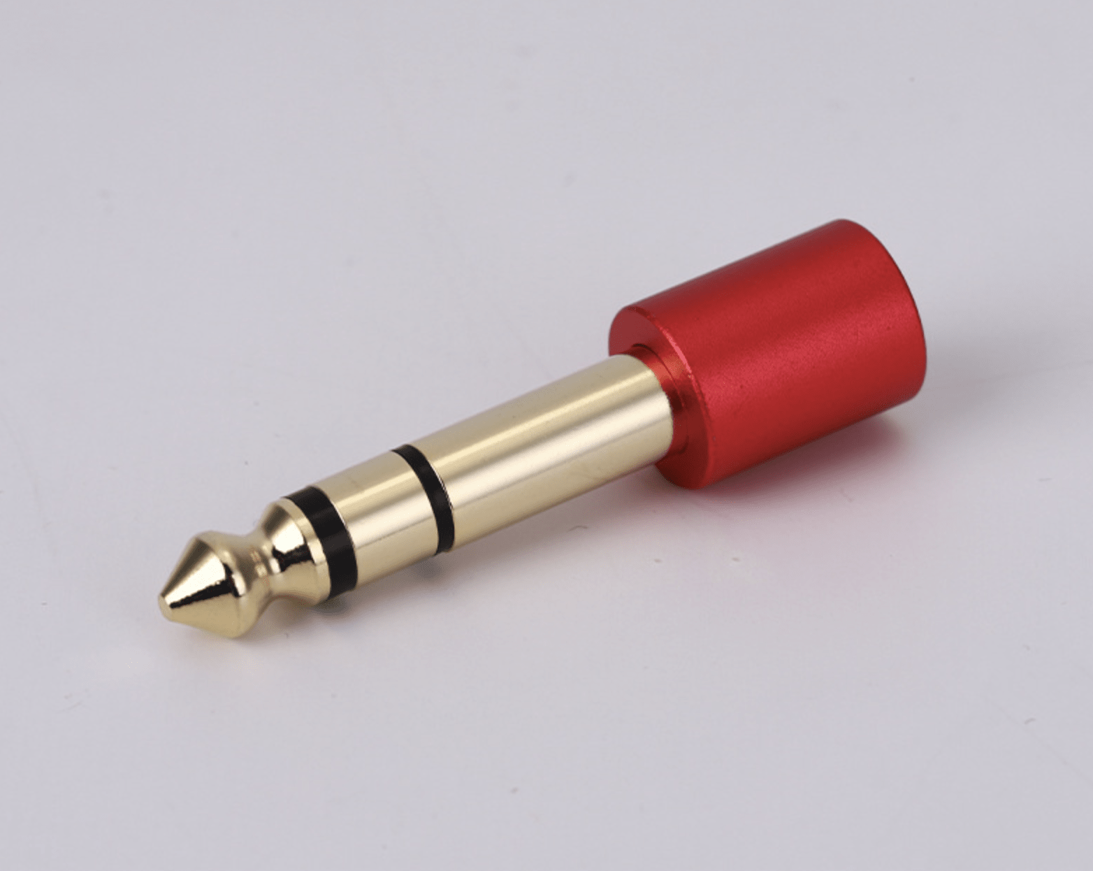Gold and red audio plug on a light gray background