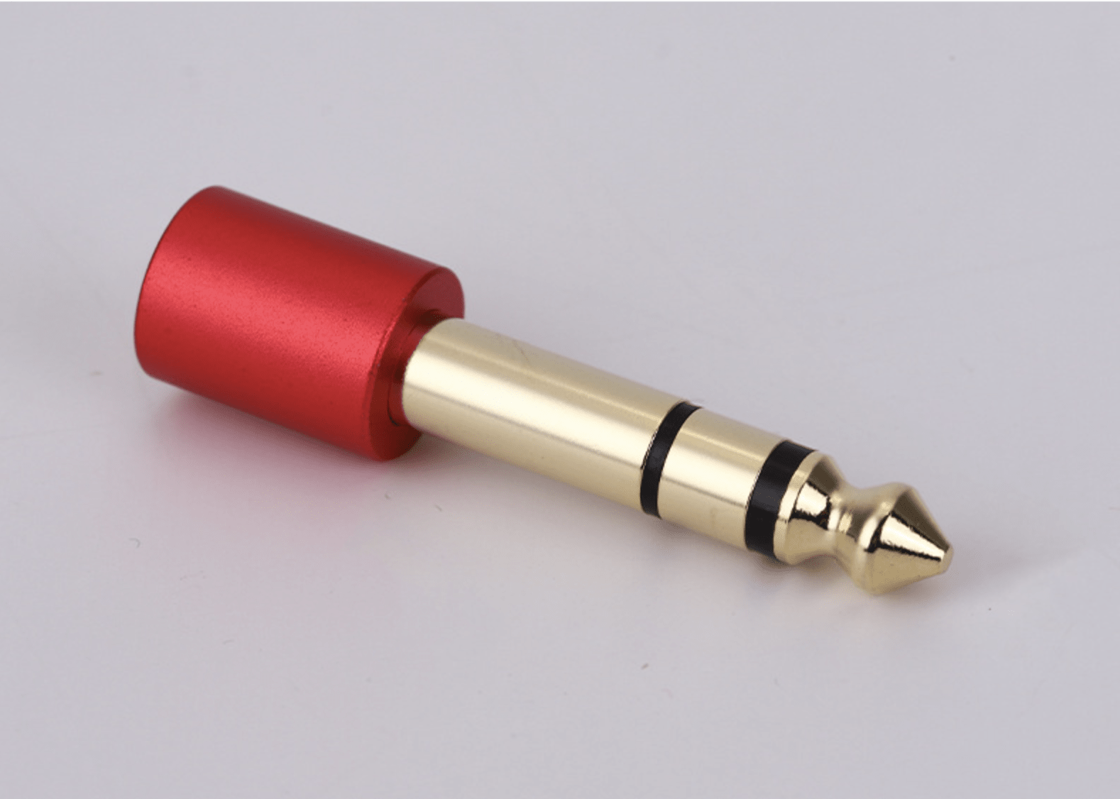 Red and gold audio plug on a light gray background
