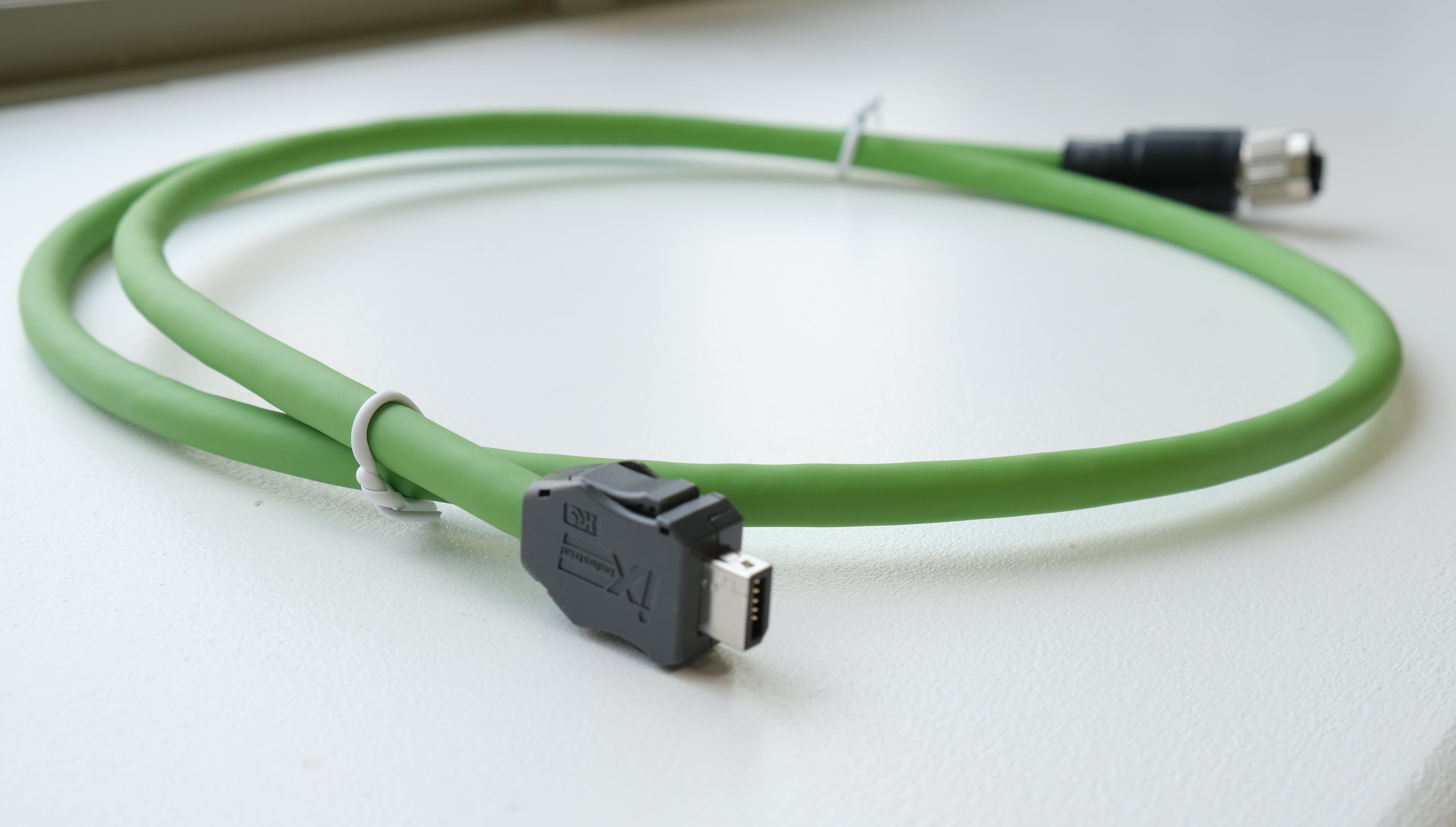 Green cable with black connectors on a white surface