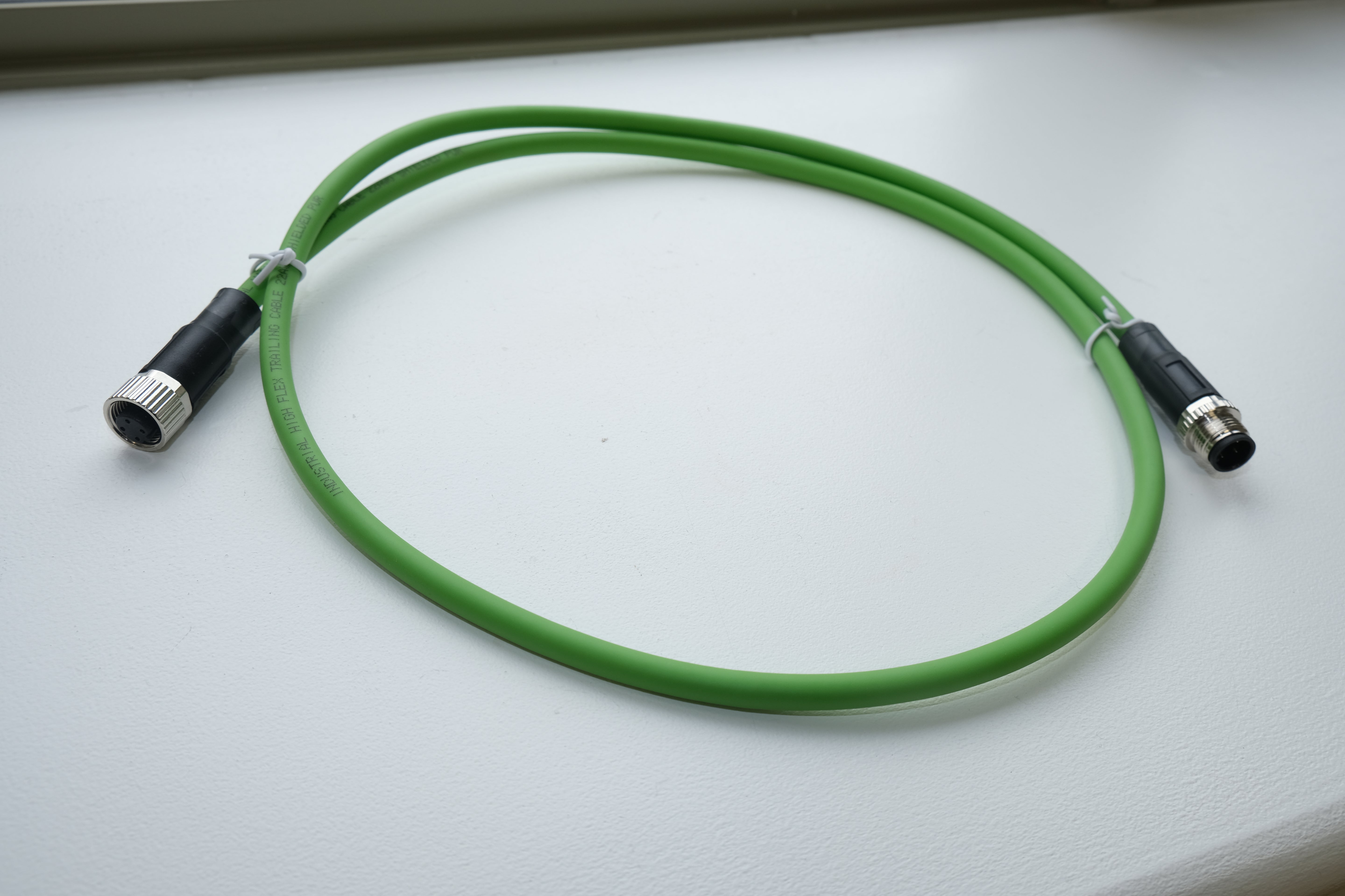 Green cable with black connectors on a light gray background
