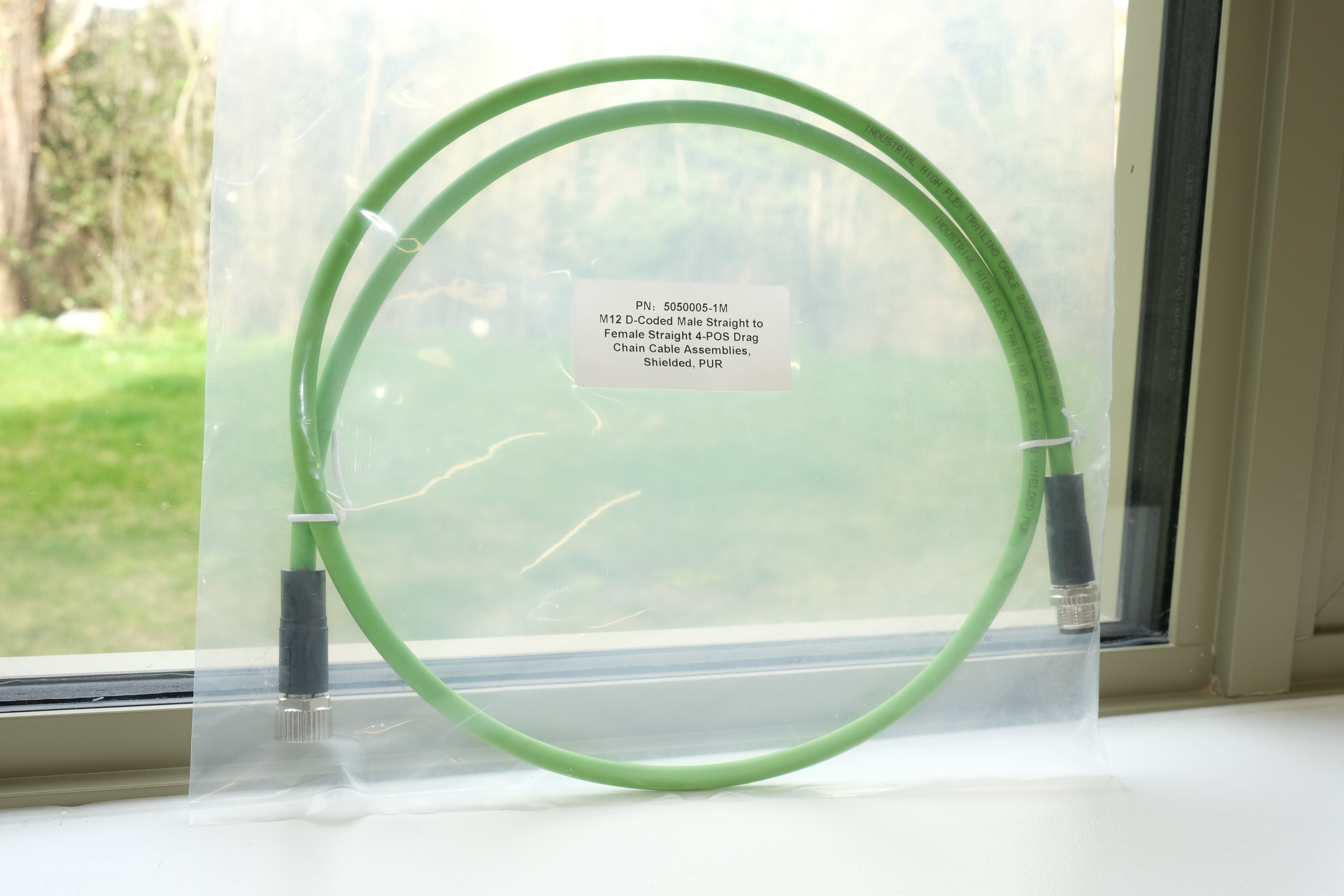 Green cable on a clear stand with a window in the background