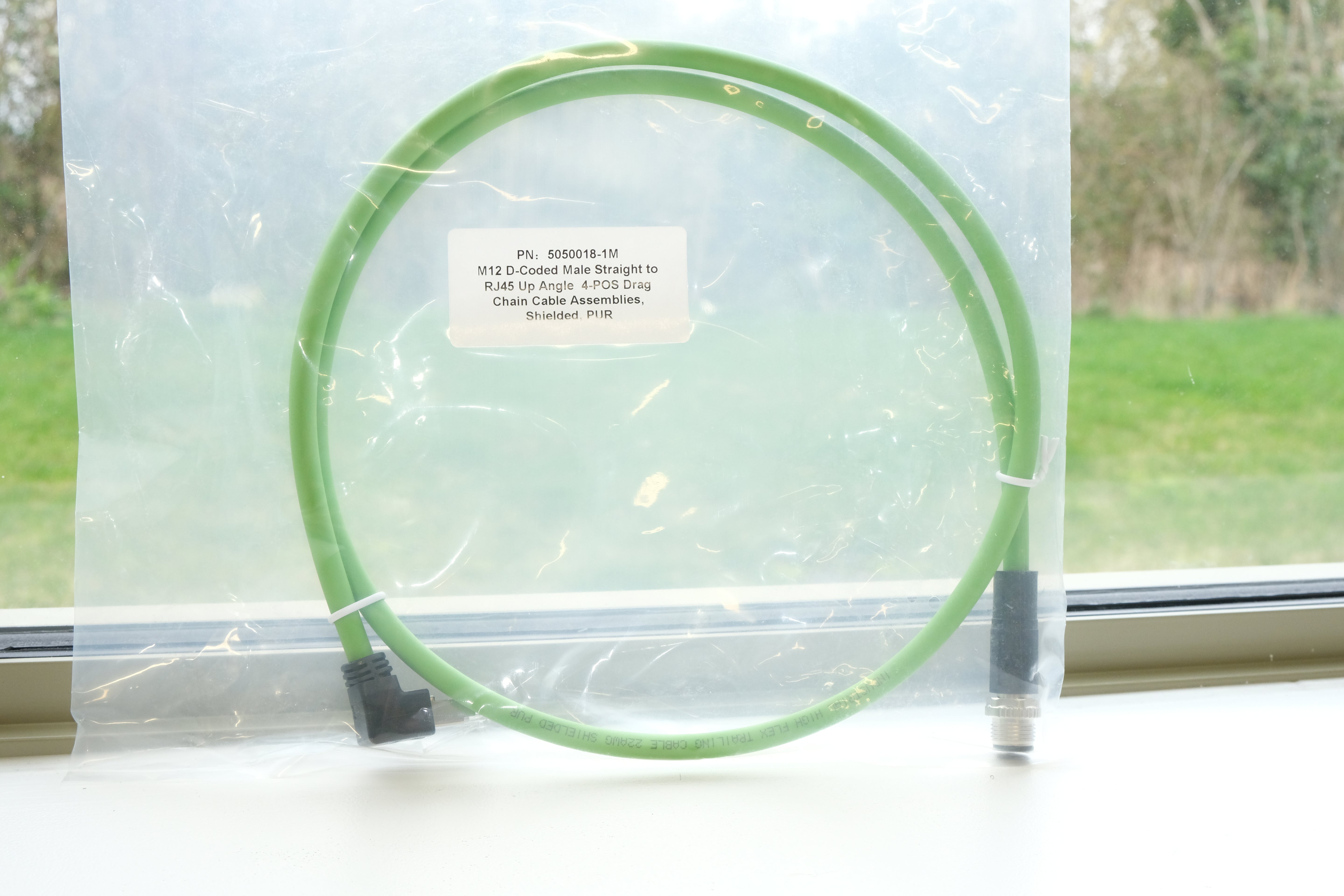 Circular green object with text label on a white surface, with a window in the background.