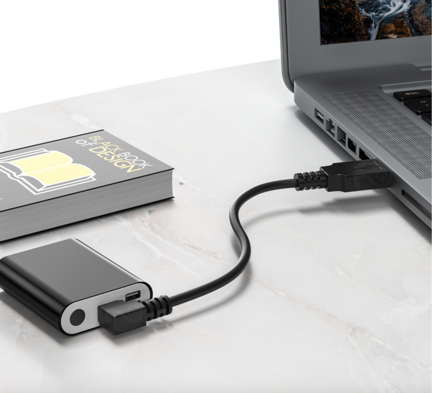 Laptop connected to a USB drive on a white surface with a book in the background