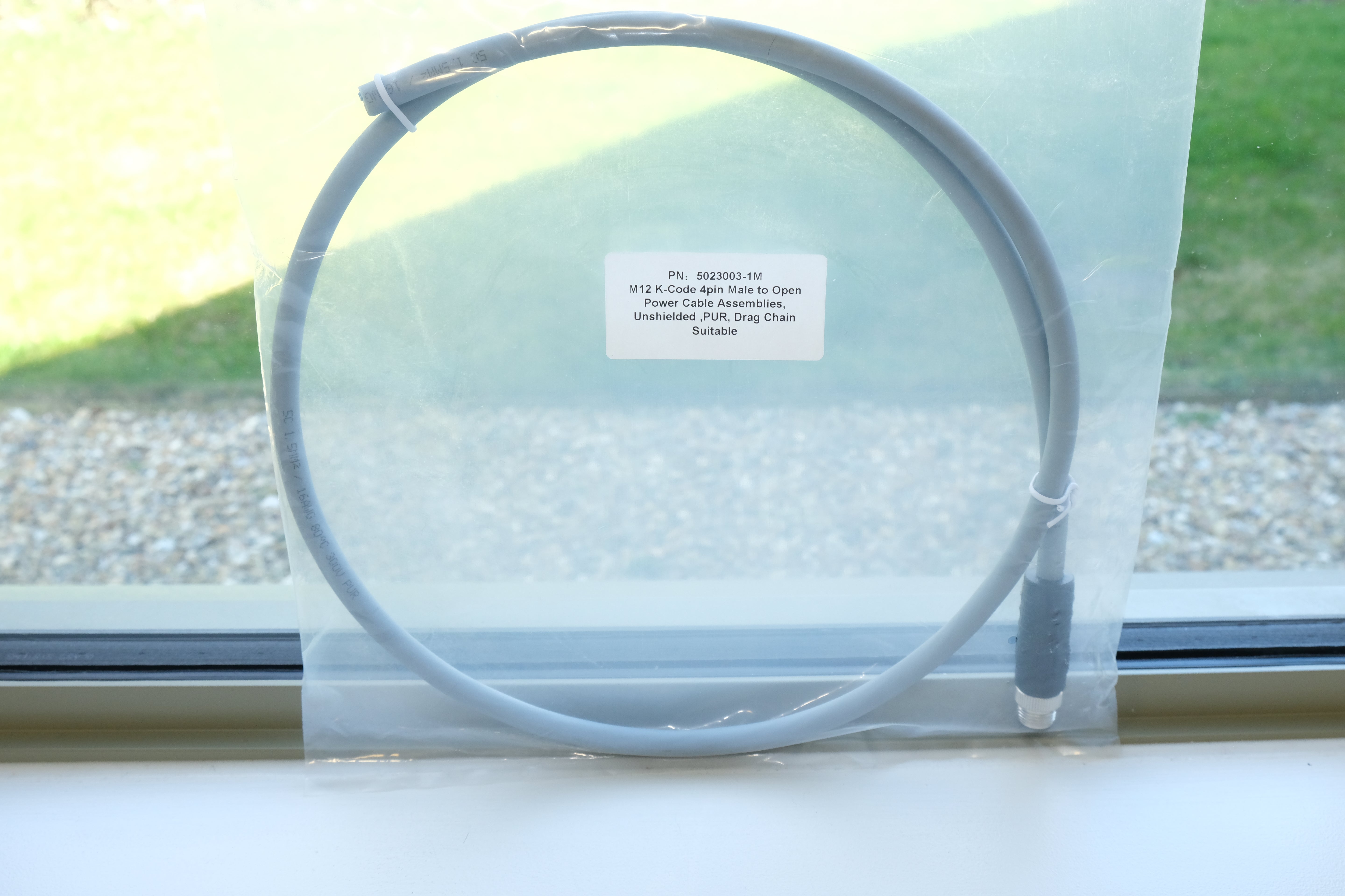 Gray cable on a white surface with a blurred outdoor background
