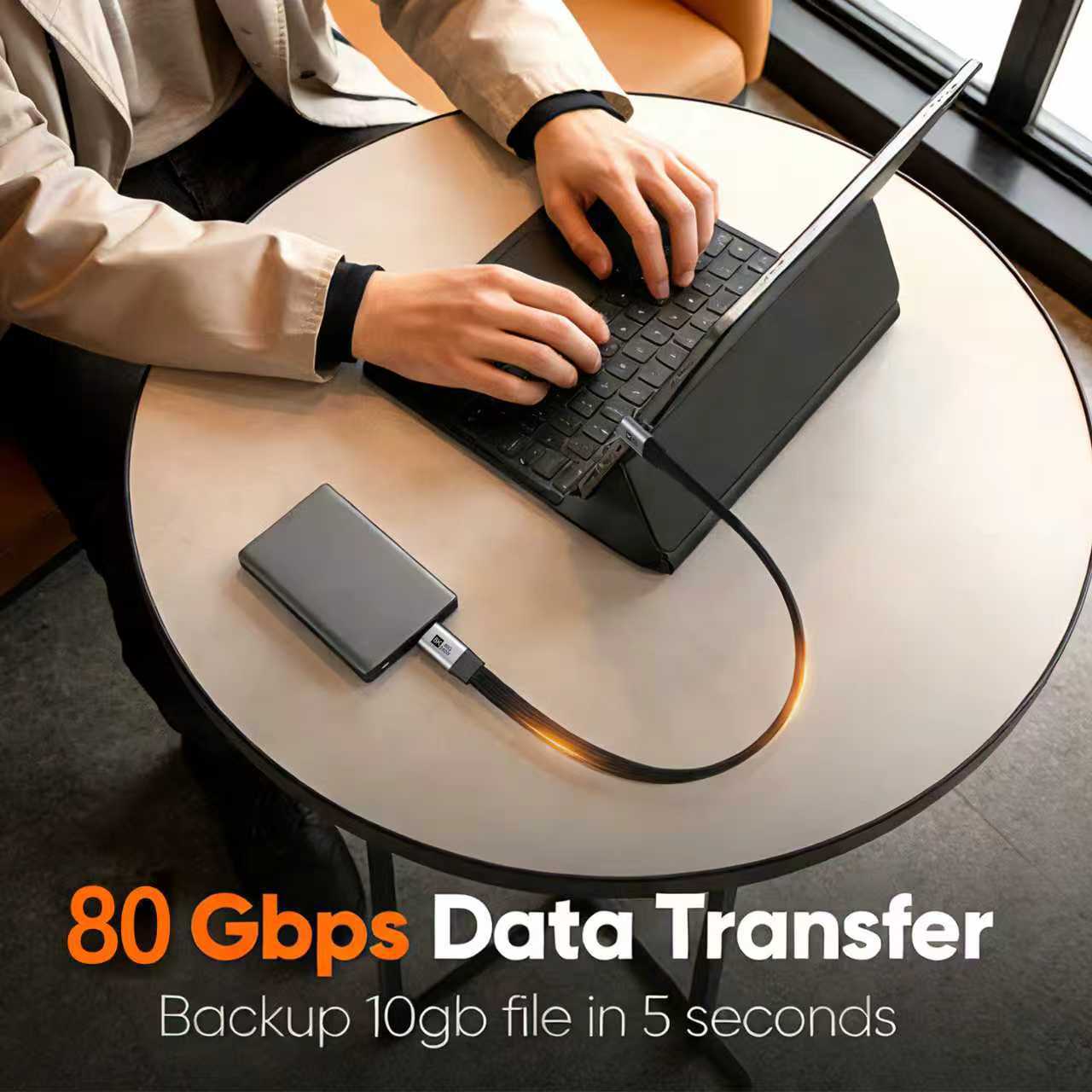 Person using a laptop with an external hard drive connected, emphasizing 80 Gbps data transfer speed.