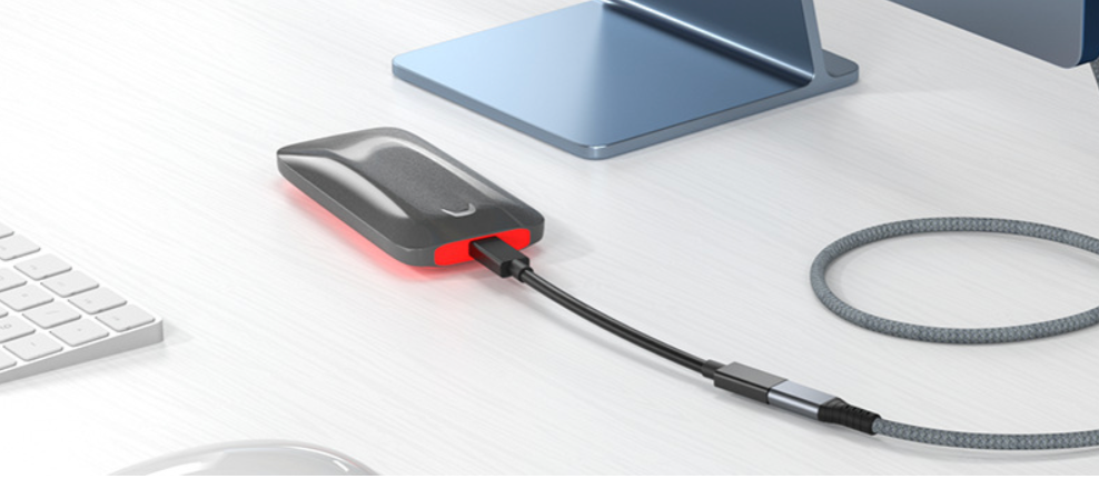 USB drive with cable on a desk next to a computer