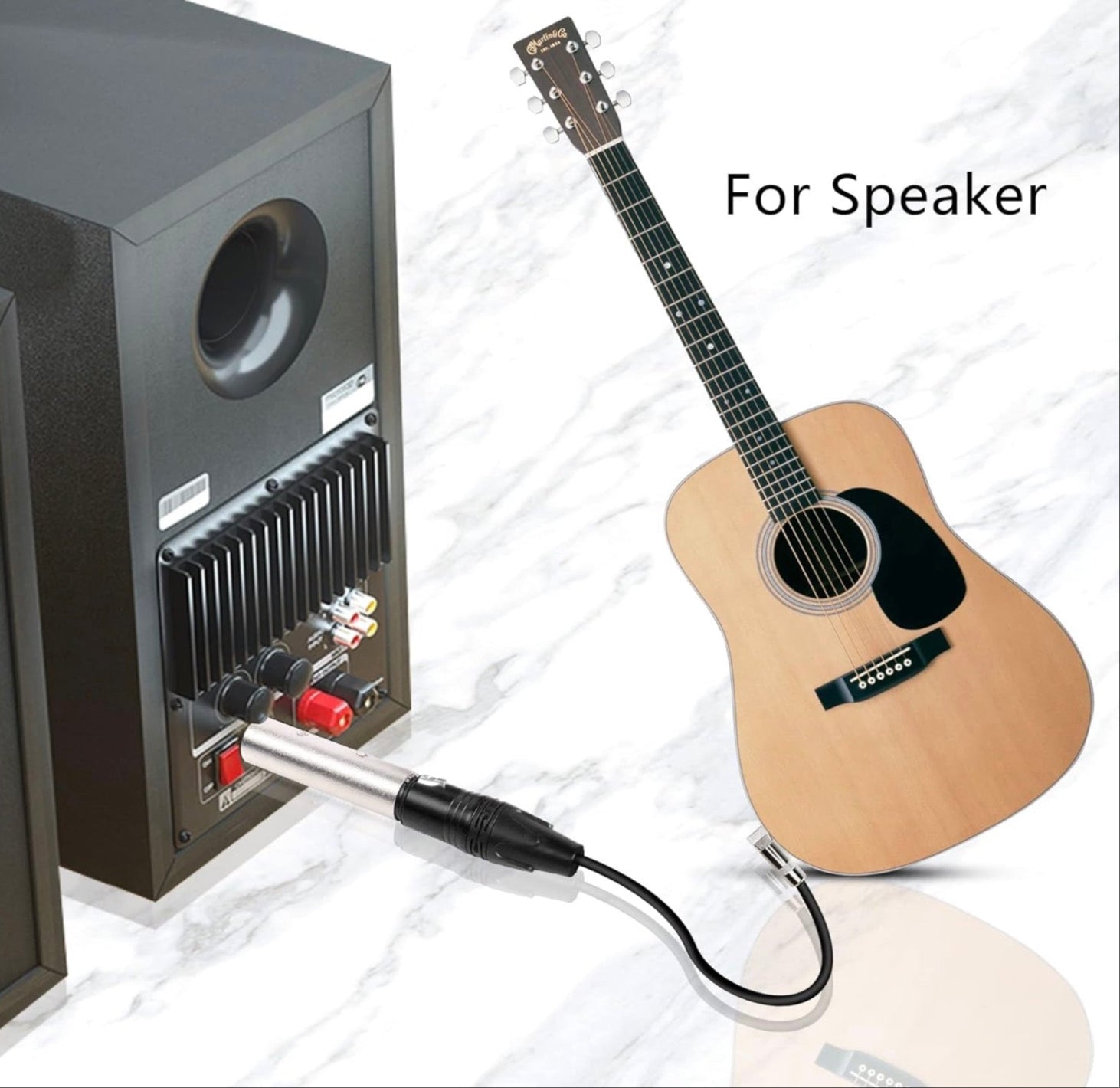 Acoustic guitar with audio cable connected to a speaker on a white background.