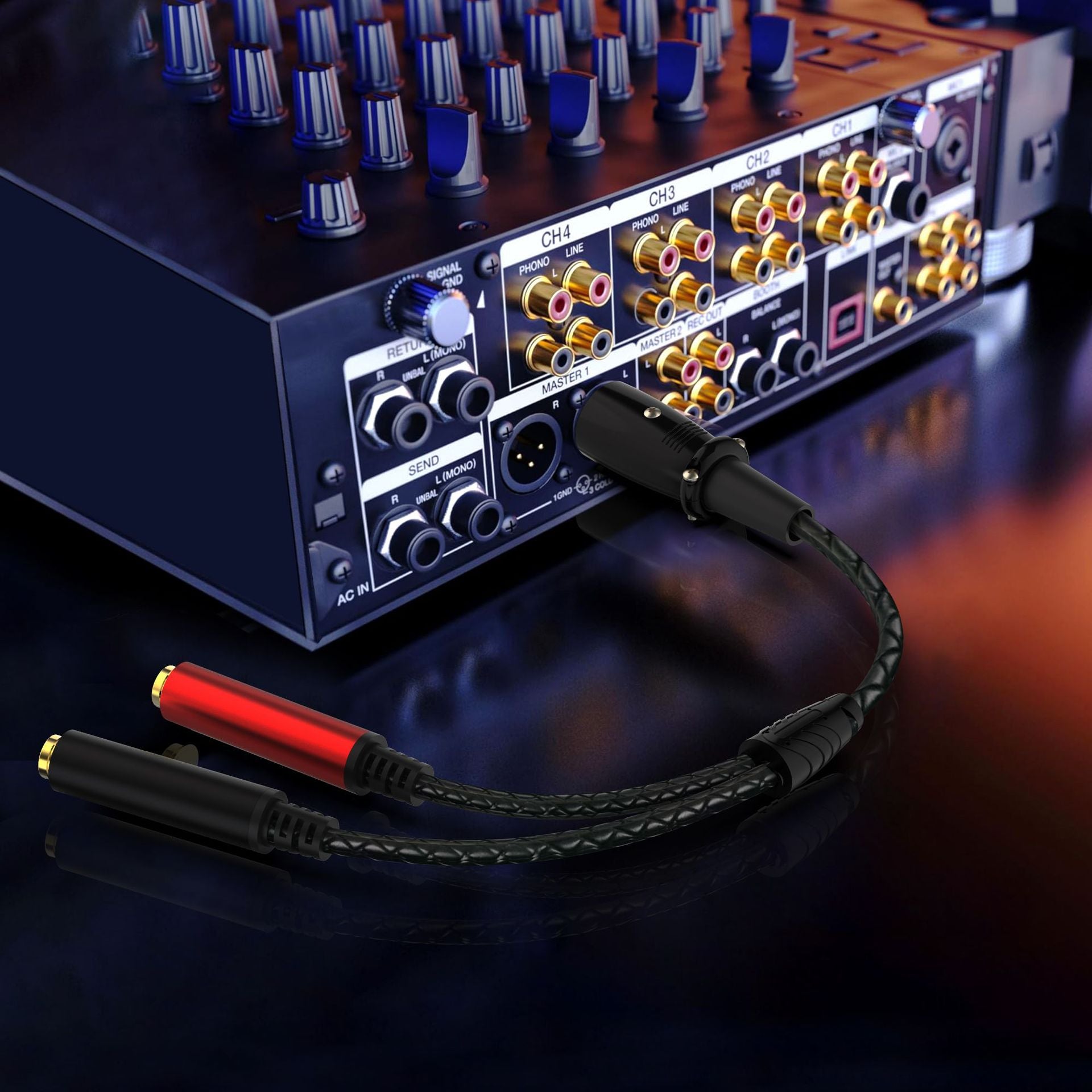 A close-up of an audio adapter cable connected to the rear panel of a multi-channel mixer or amplifier. The cable has black plugs with one red accent ring and gold-plated tips, attached to a black braided cable.
