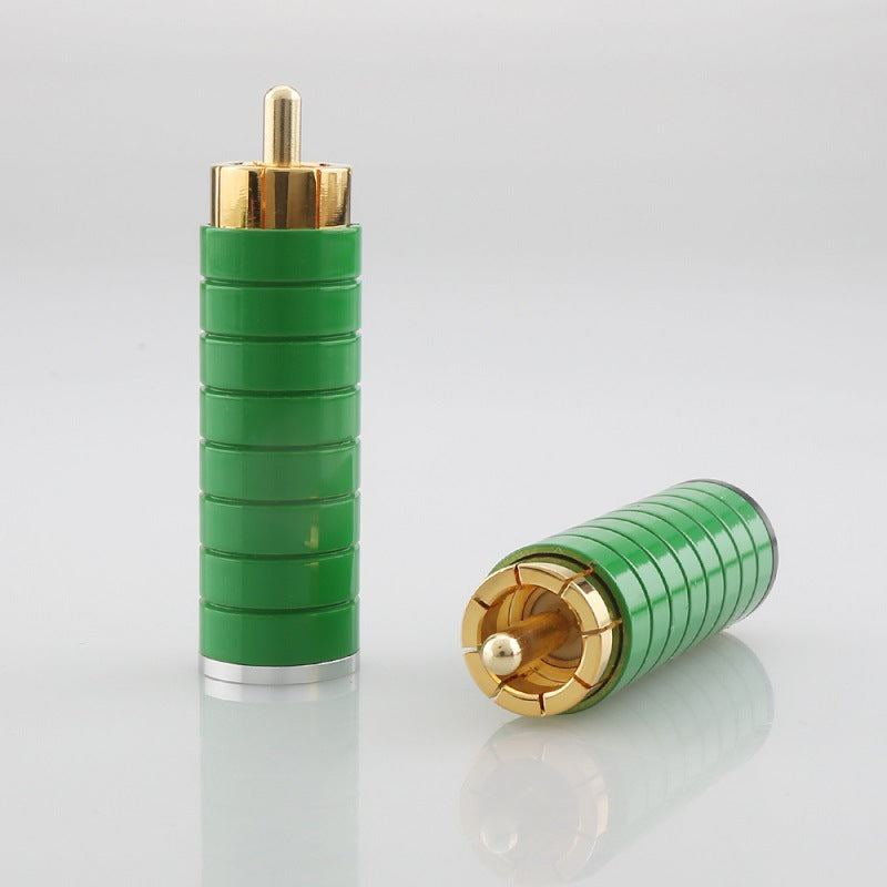 Two green and gold cylindrical connectors on a light gray background