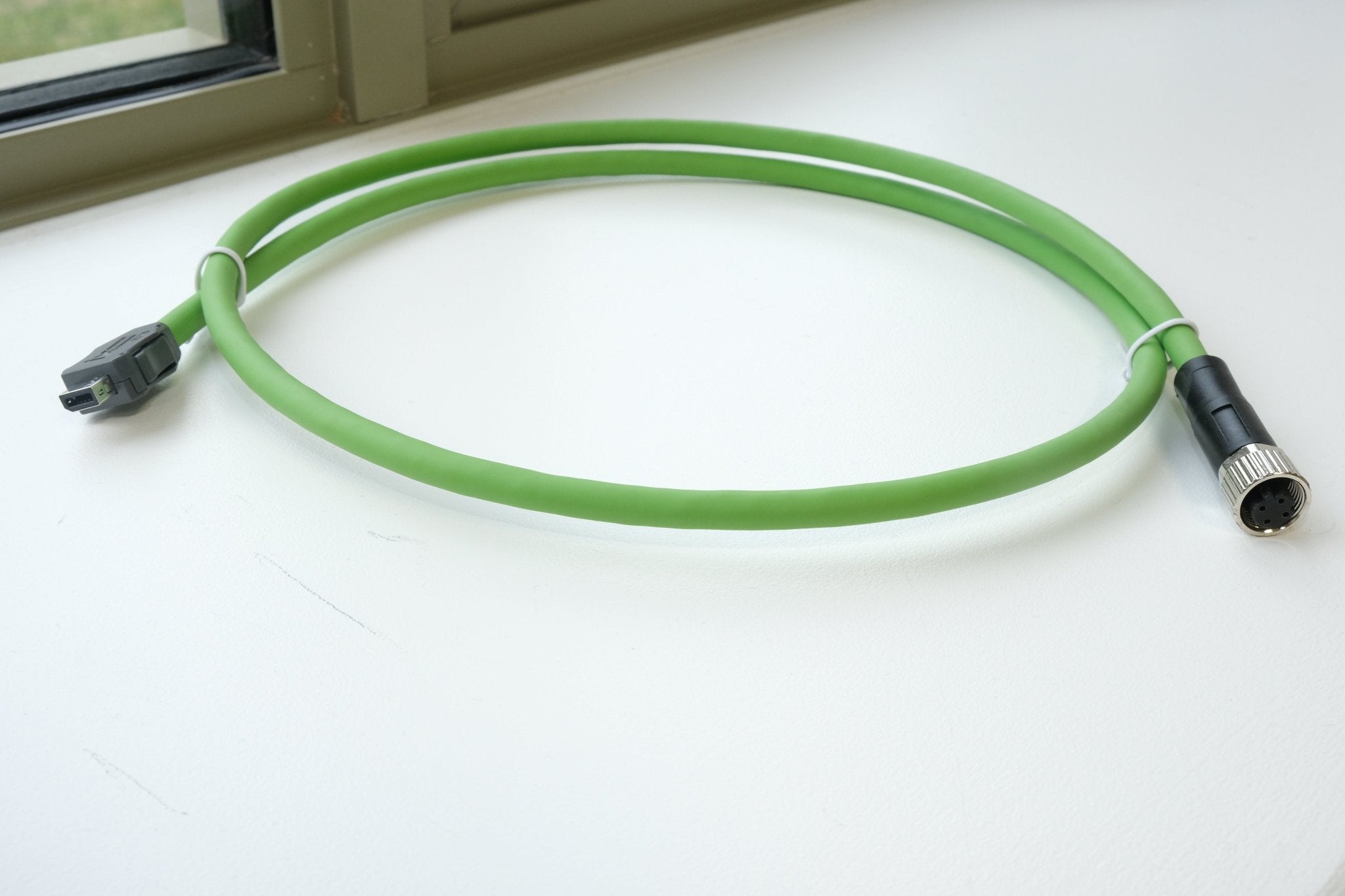 Green cable with black connectors on a white surface