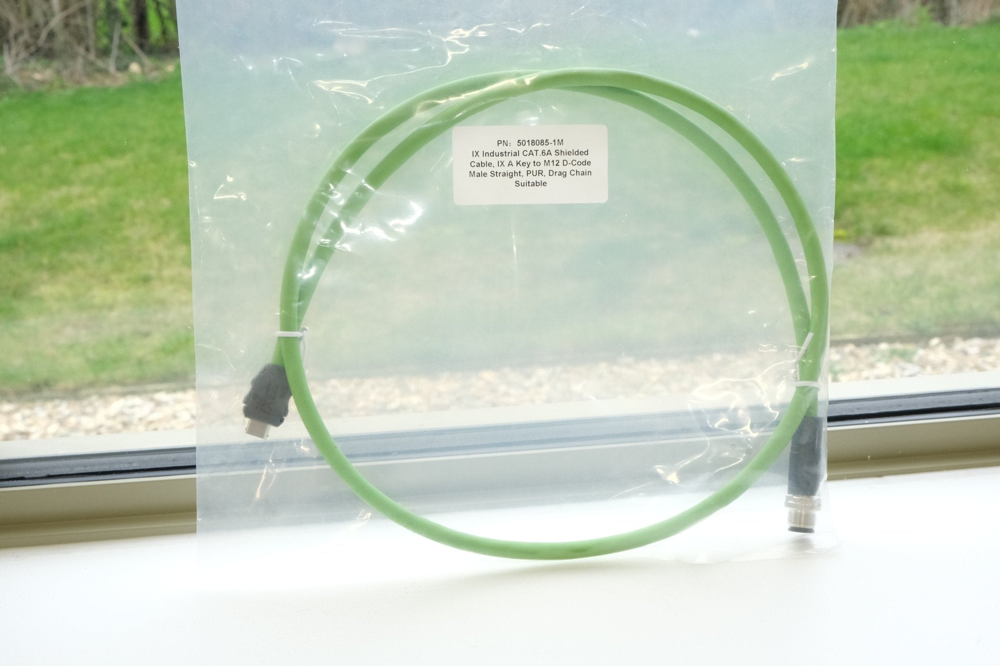 Green hoop in a clear plastic bag with grass and window sill in the background