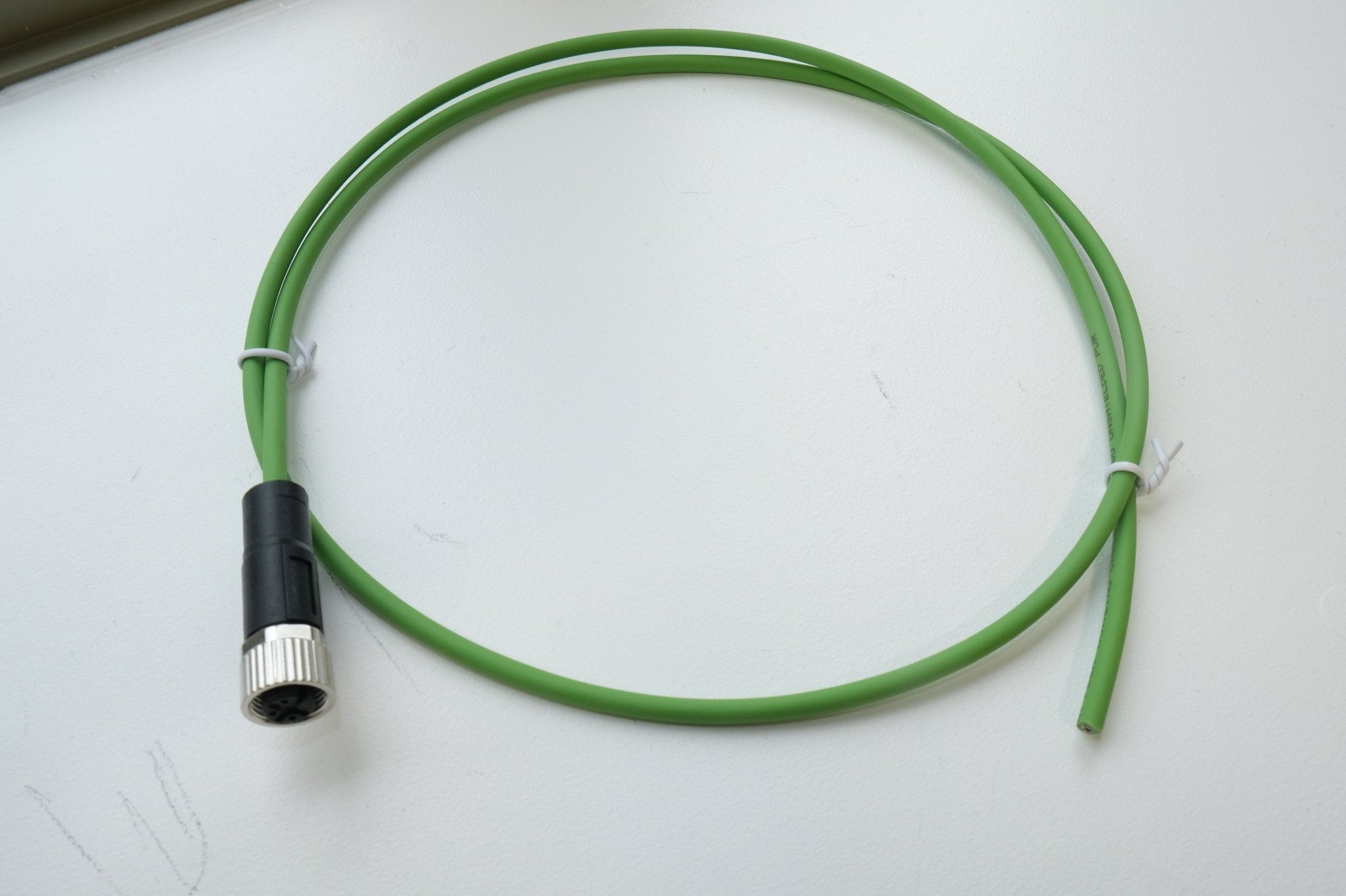 Green cable with a black and silver connector on a white background