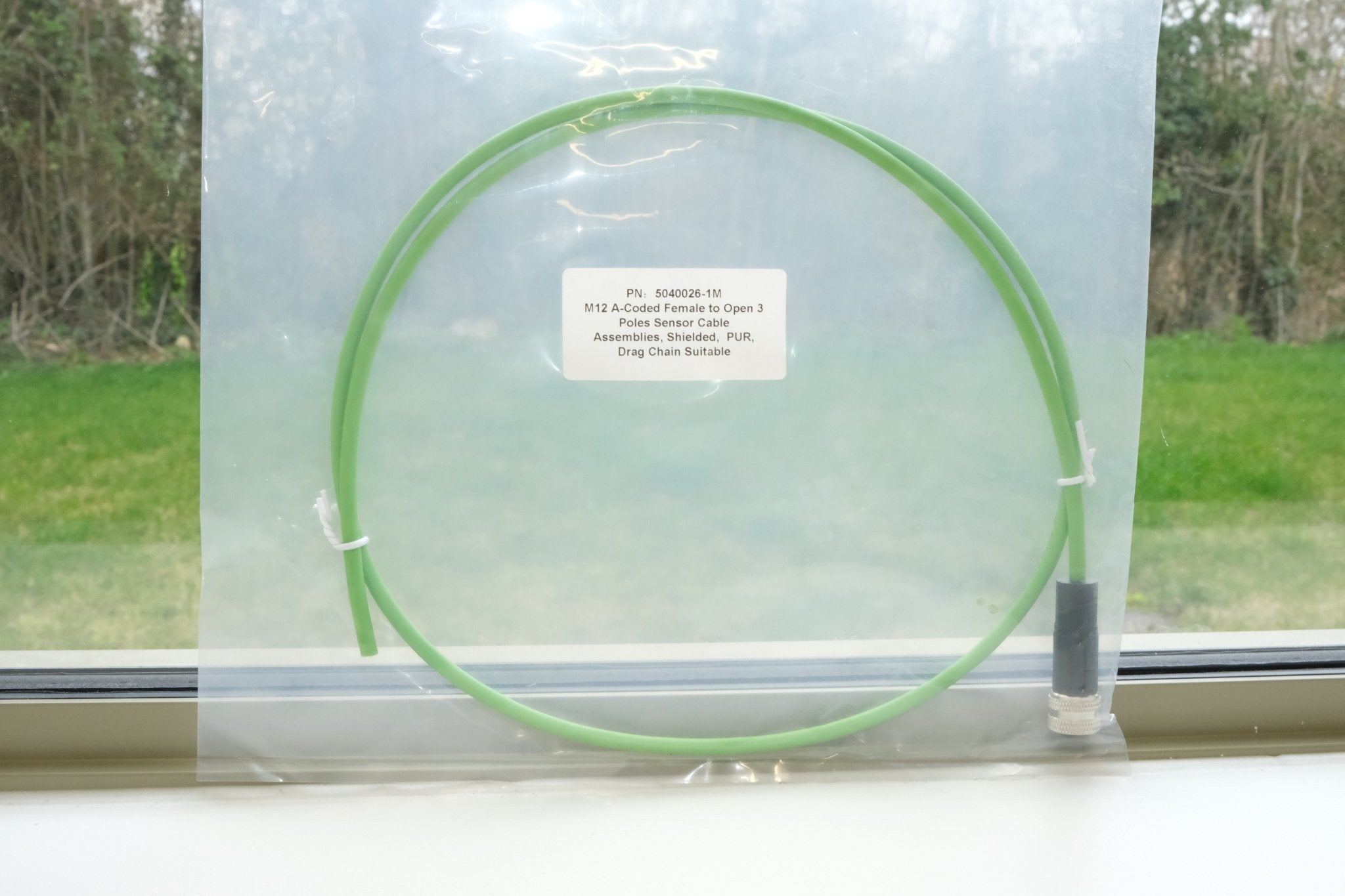 Green cable on a white surface with a window in the background