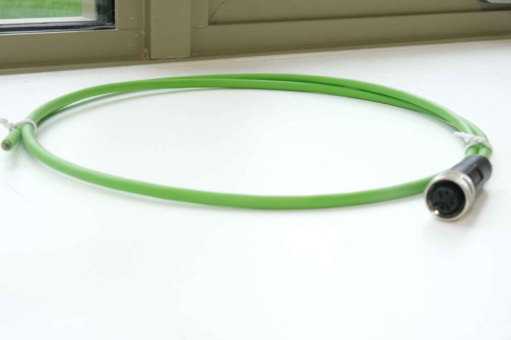Green cable with a connector on a white surface
