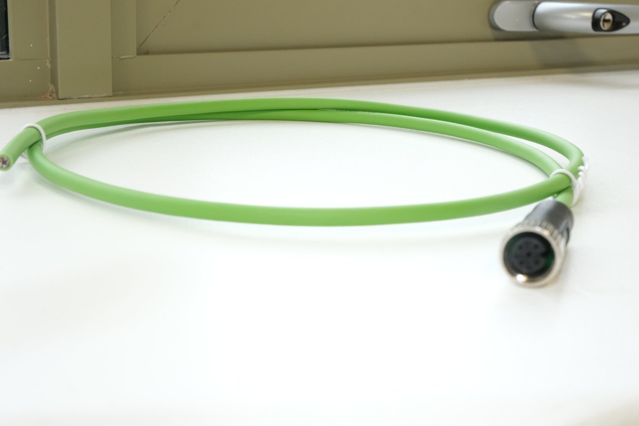 Green cable with a metal connector on a white surface