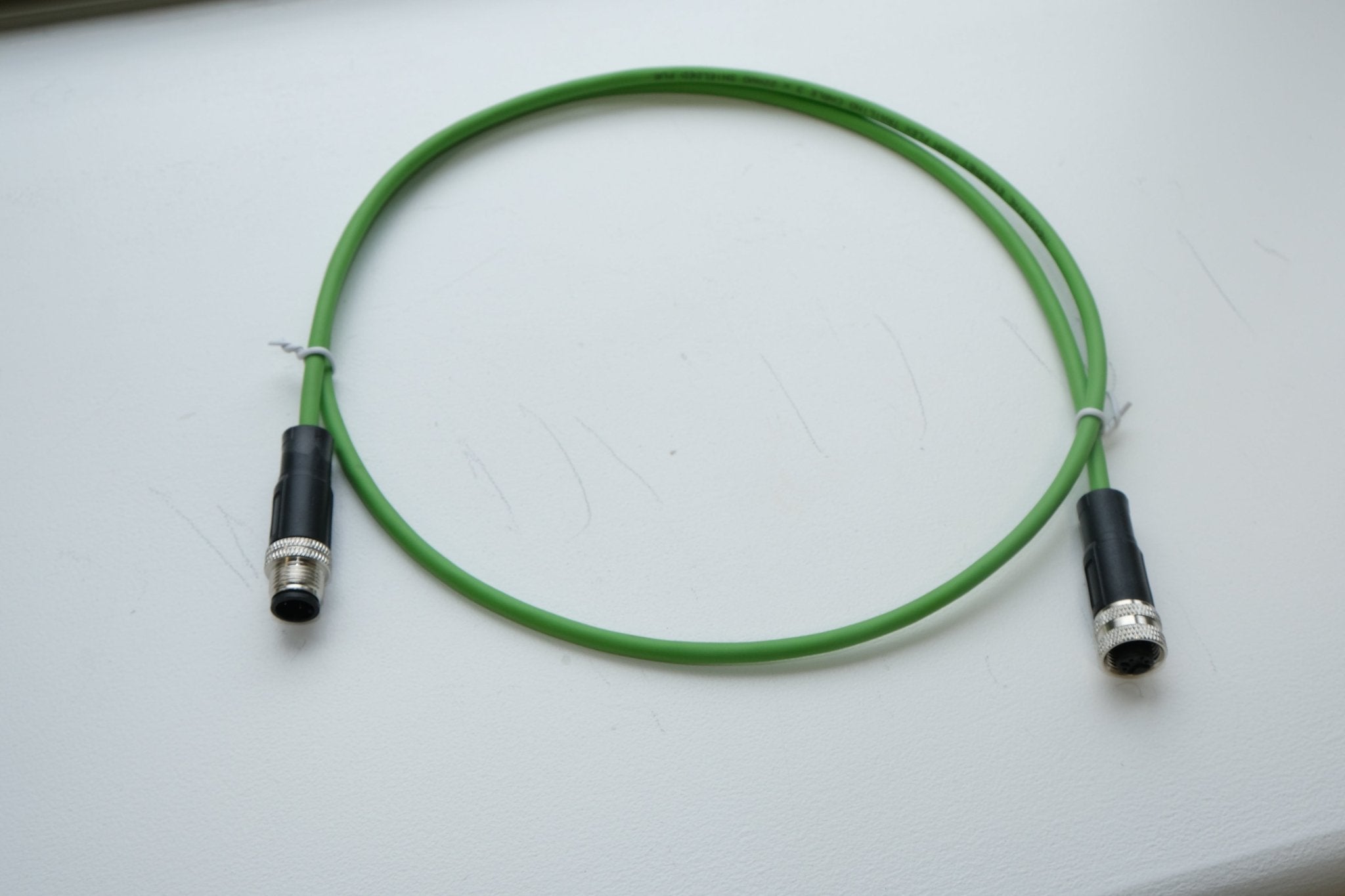 Green cable with black connectors on a white background