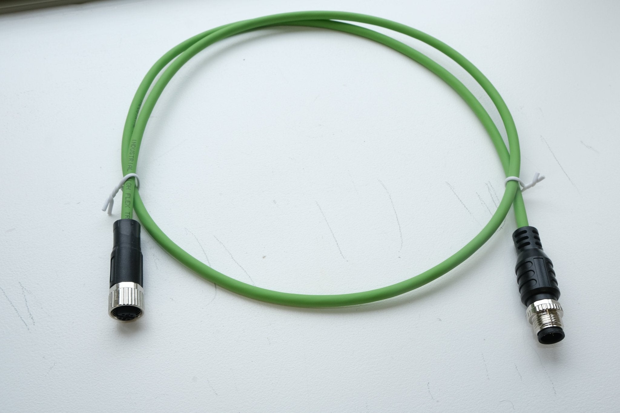 Green cable with black connectors on a white background
