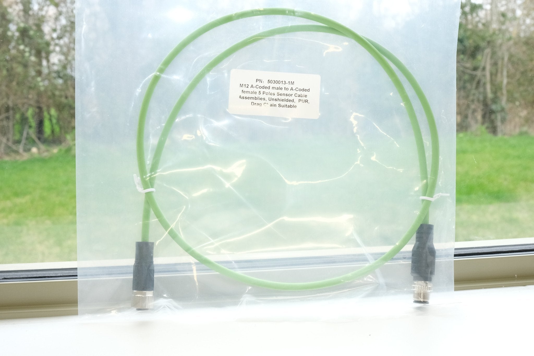 Green cable on a clear background with a window and outdoor view in the background