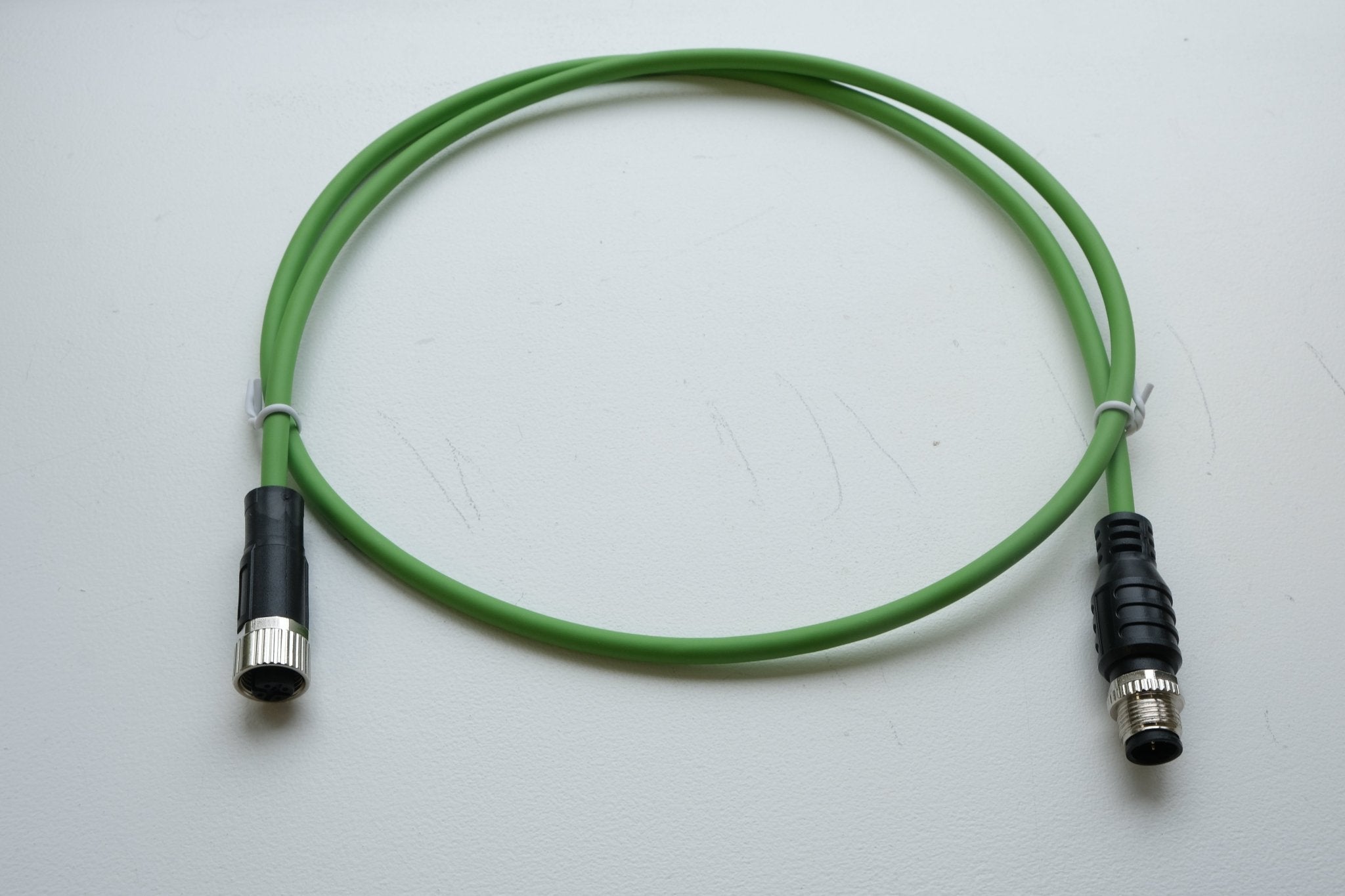 Green cable with black connectors on a white background