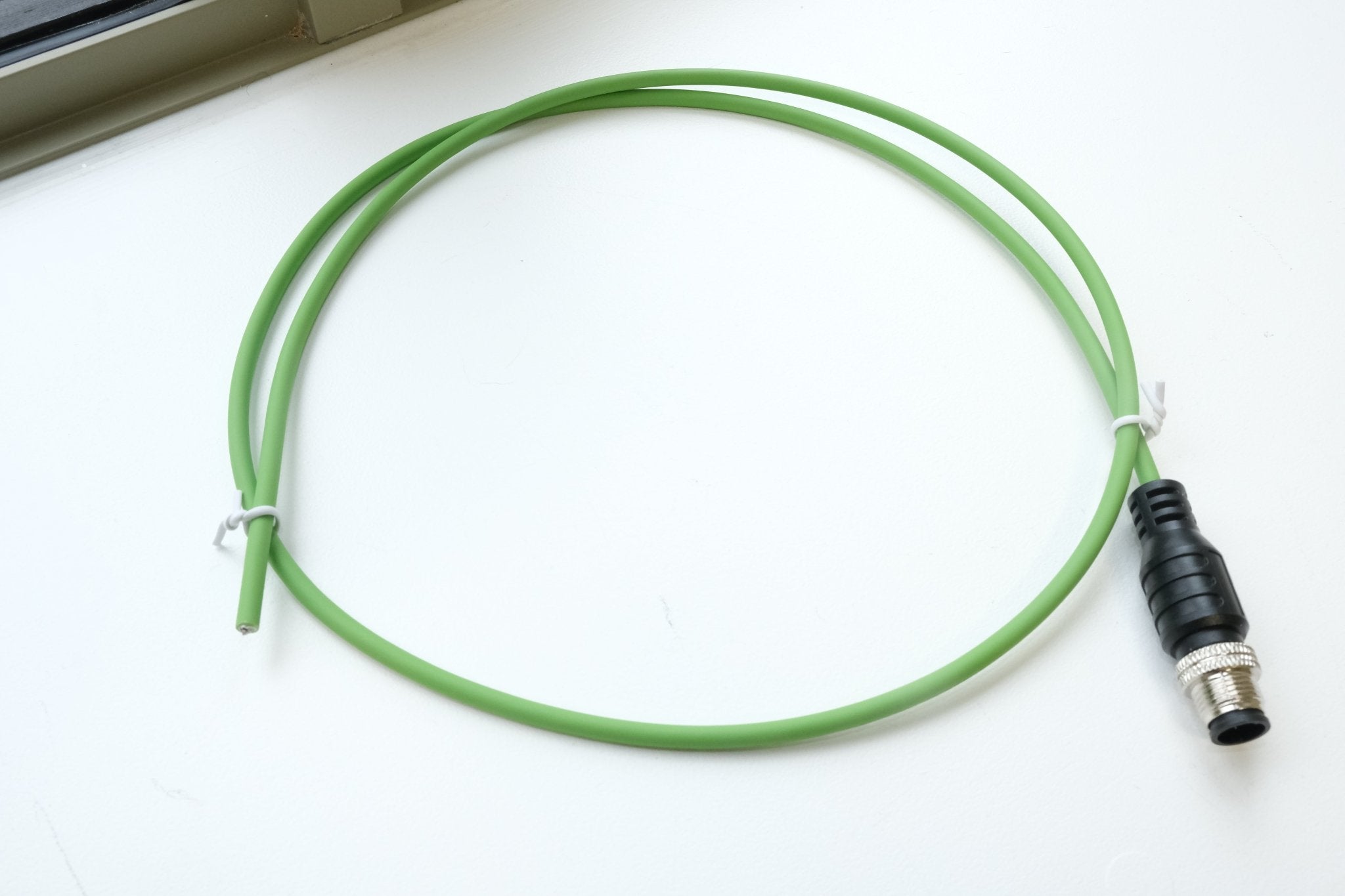 Green cable with a black connector on a white surface