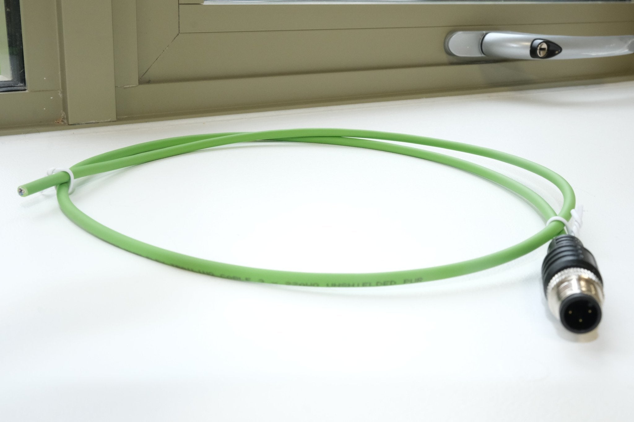 Green cable with a black connector on a white surface