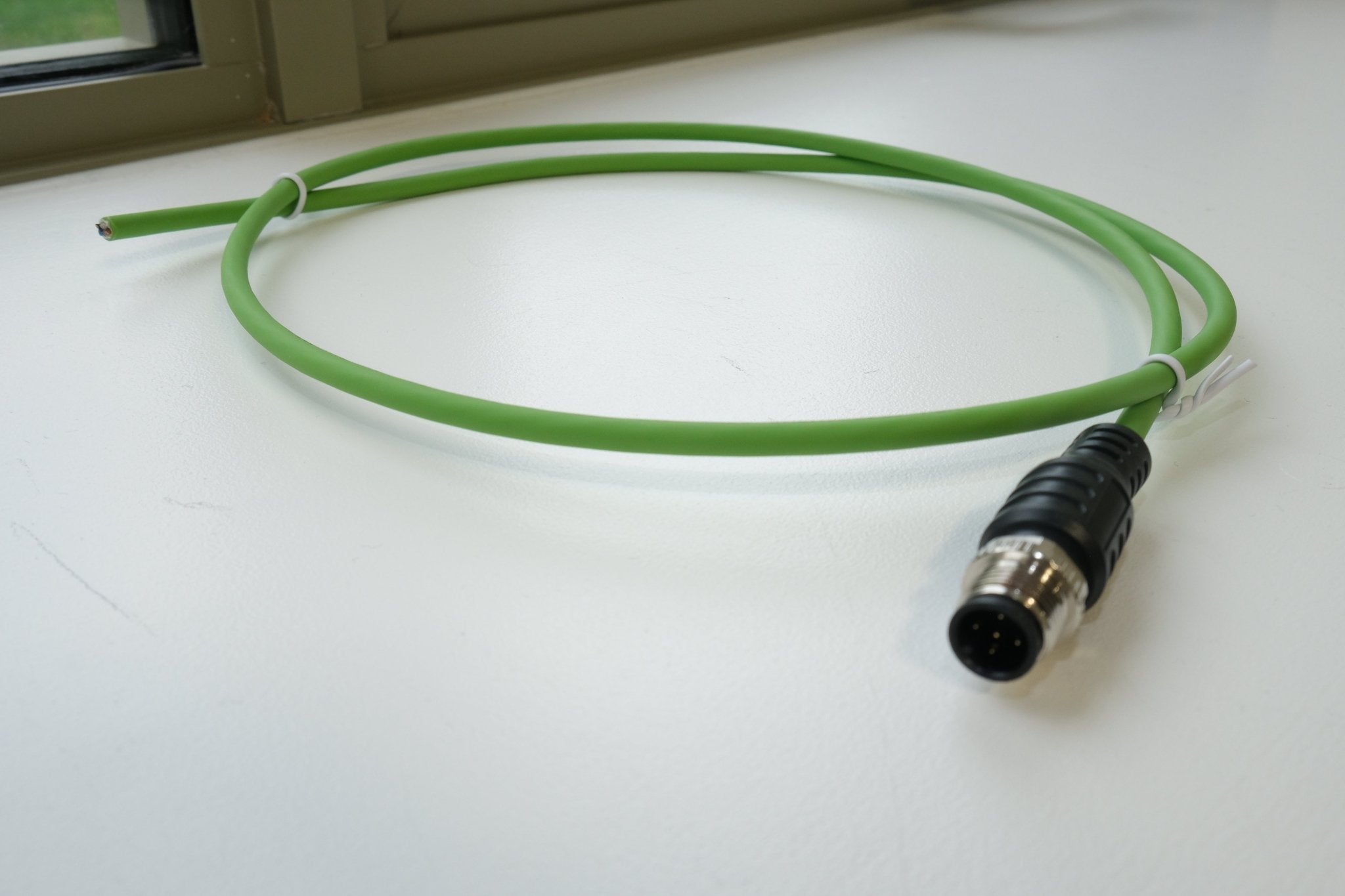 Green cable with a black connector on a white surface