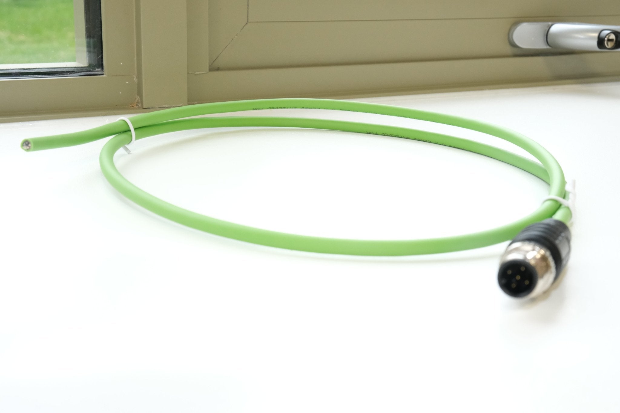 Green cable with a connector on a white surface