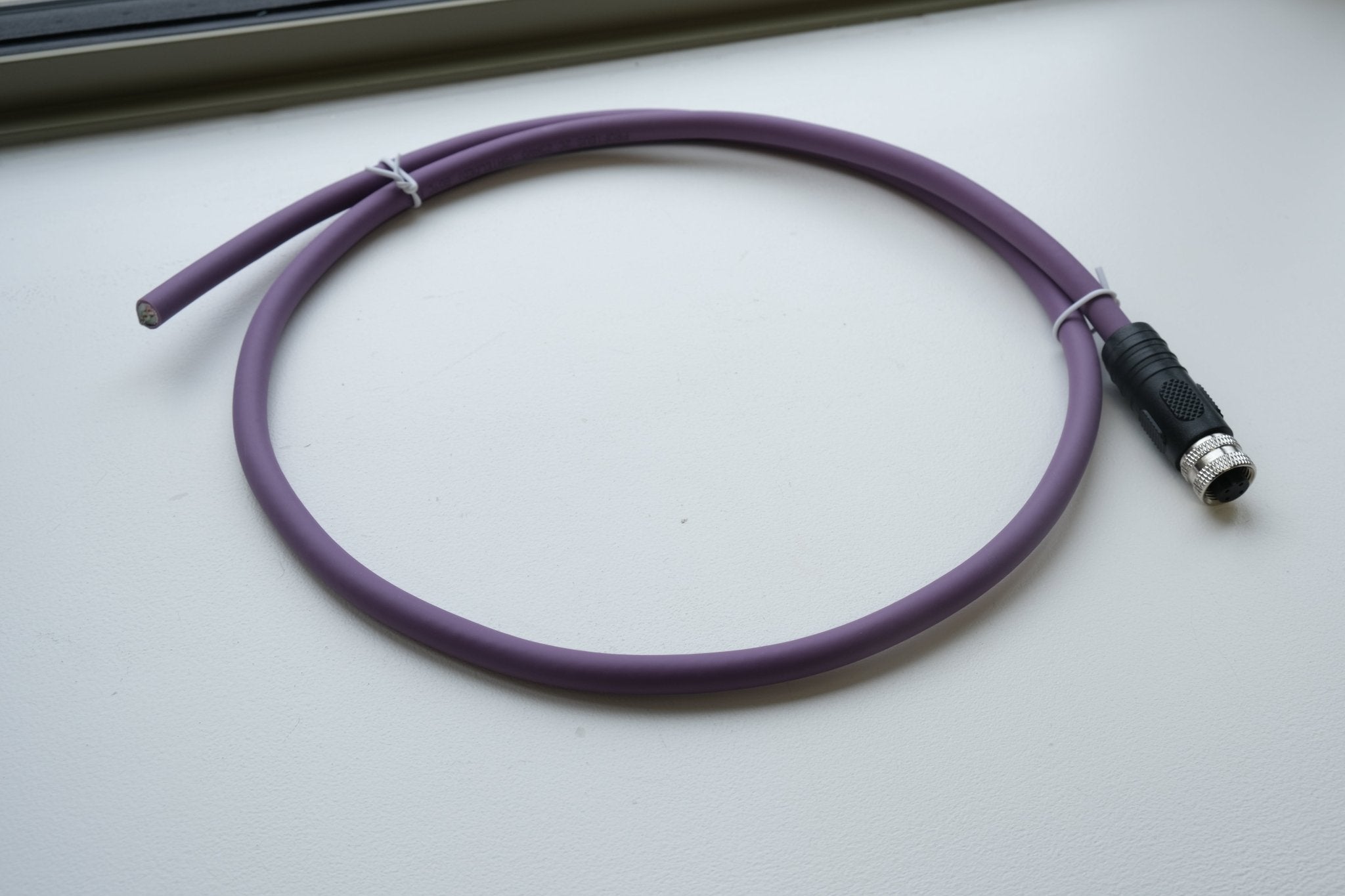 Purple cable with a black connector on a white surface