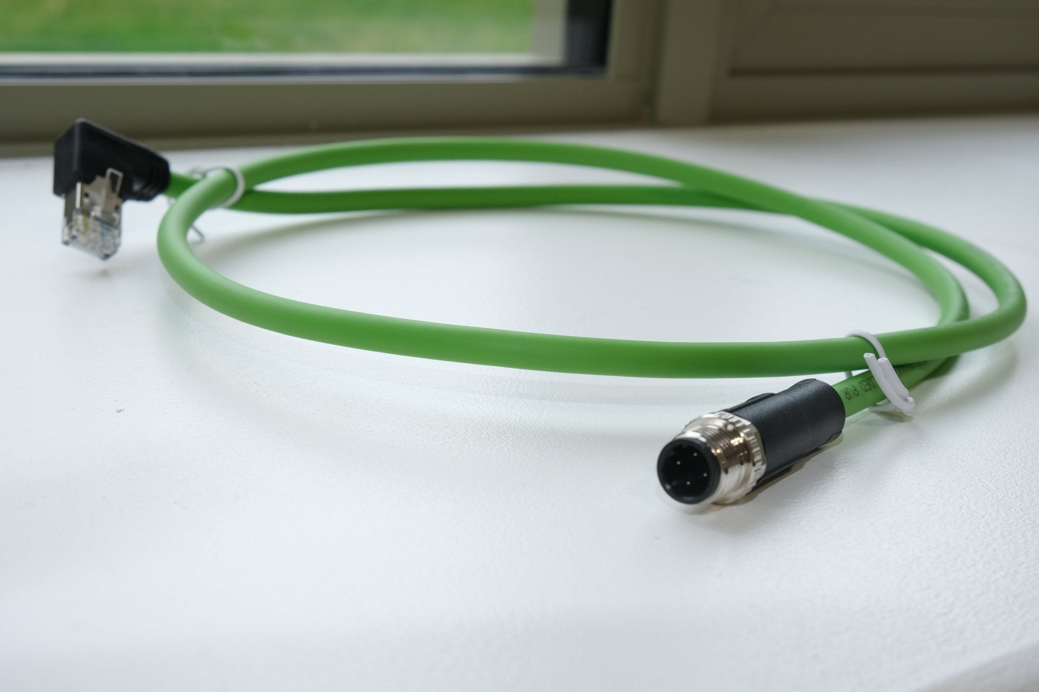 Green cable with connectors on a white surface