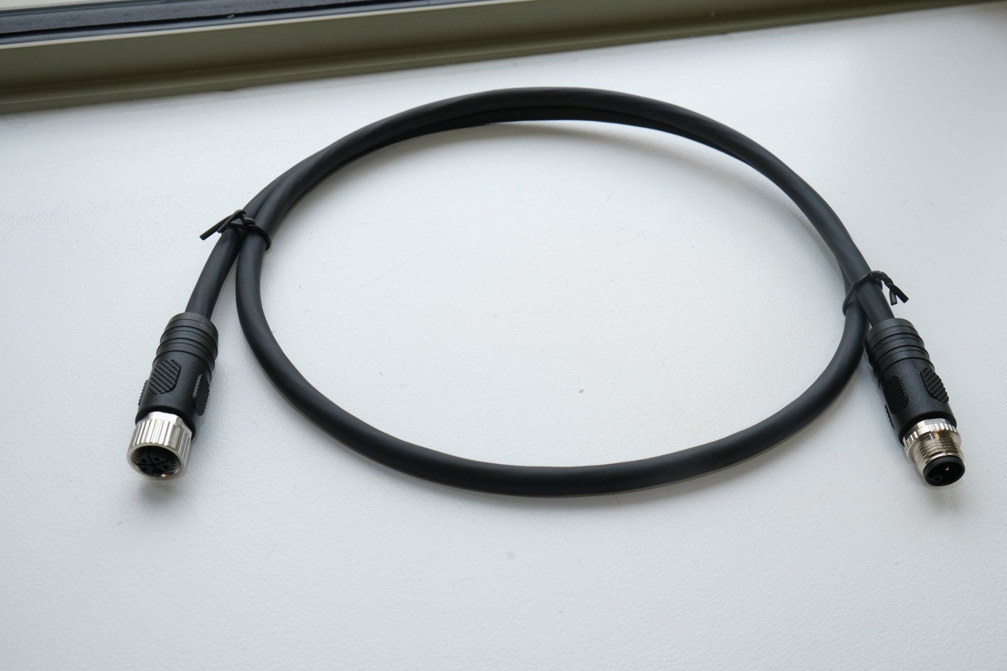 Black cable with connectors on a light gray surface