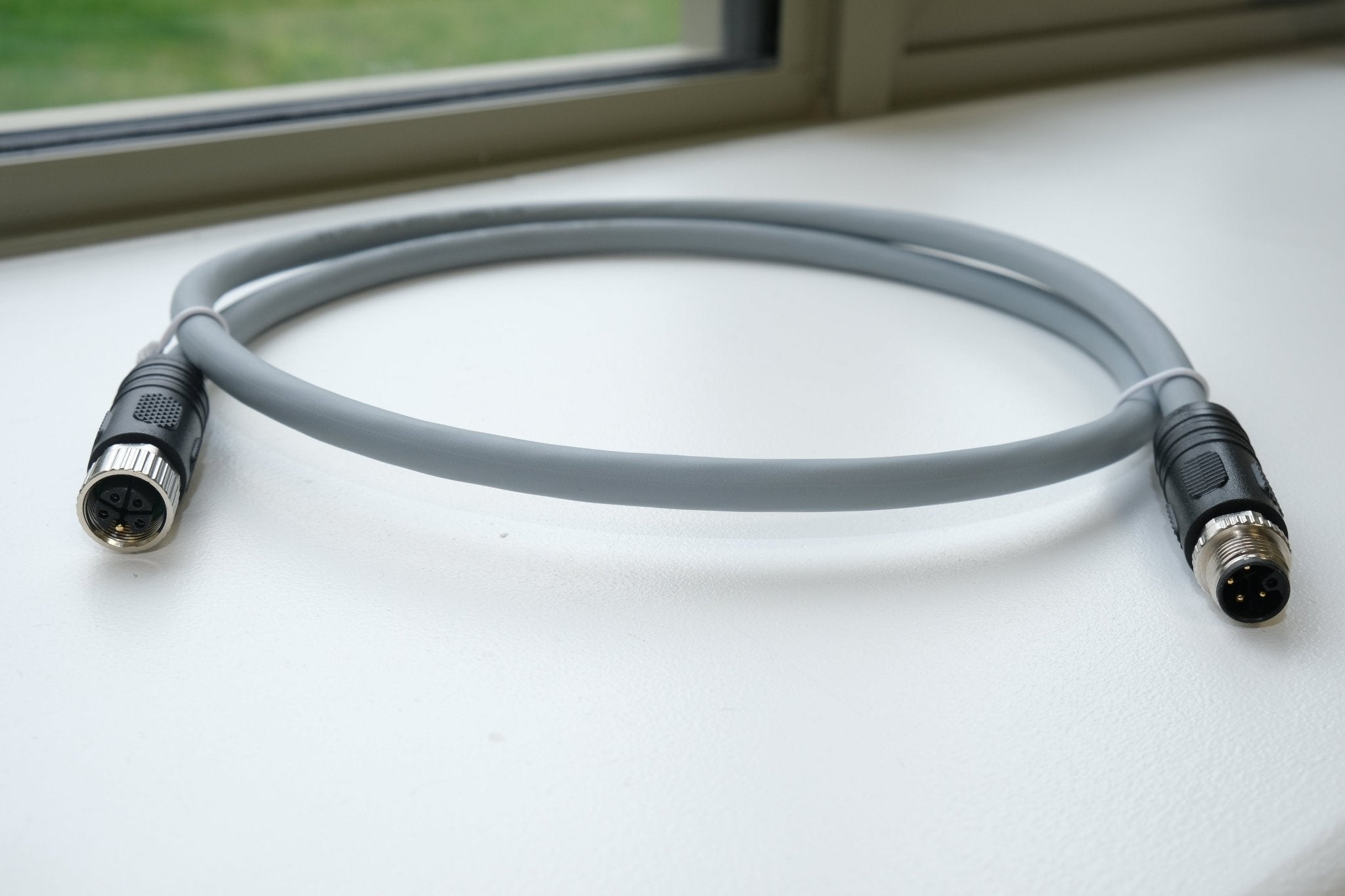 Gray cable with connectors on a white surface