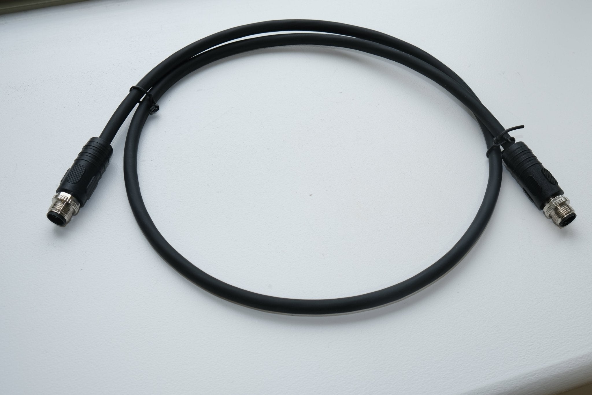 Black cable with connectors on a white surface