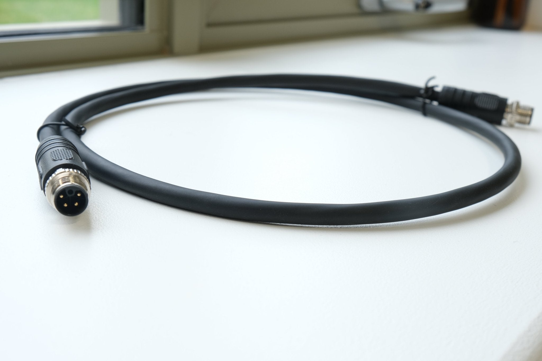 Black cable with connectors on a white surface