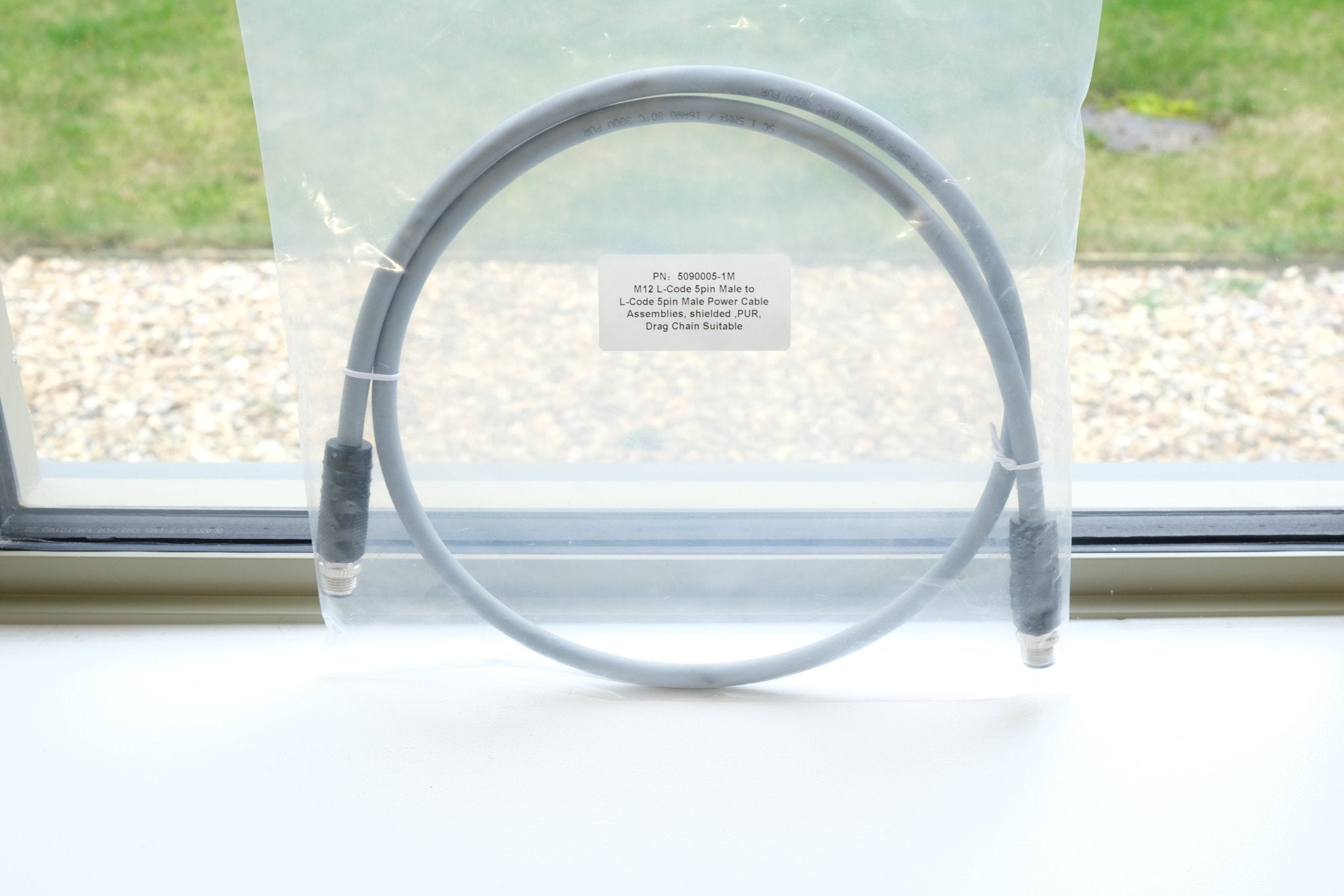 Clear plastic tube with a label on a white surface, with a window in the background.