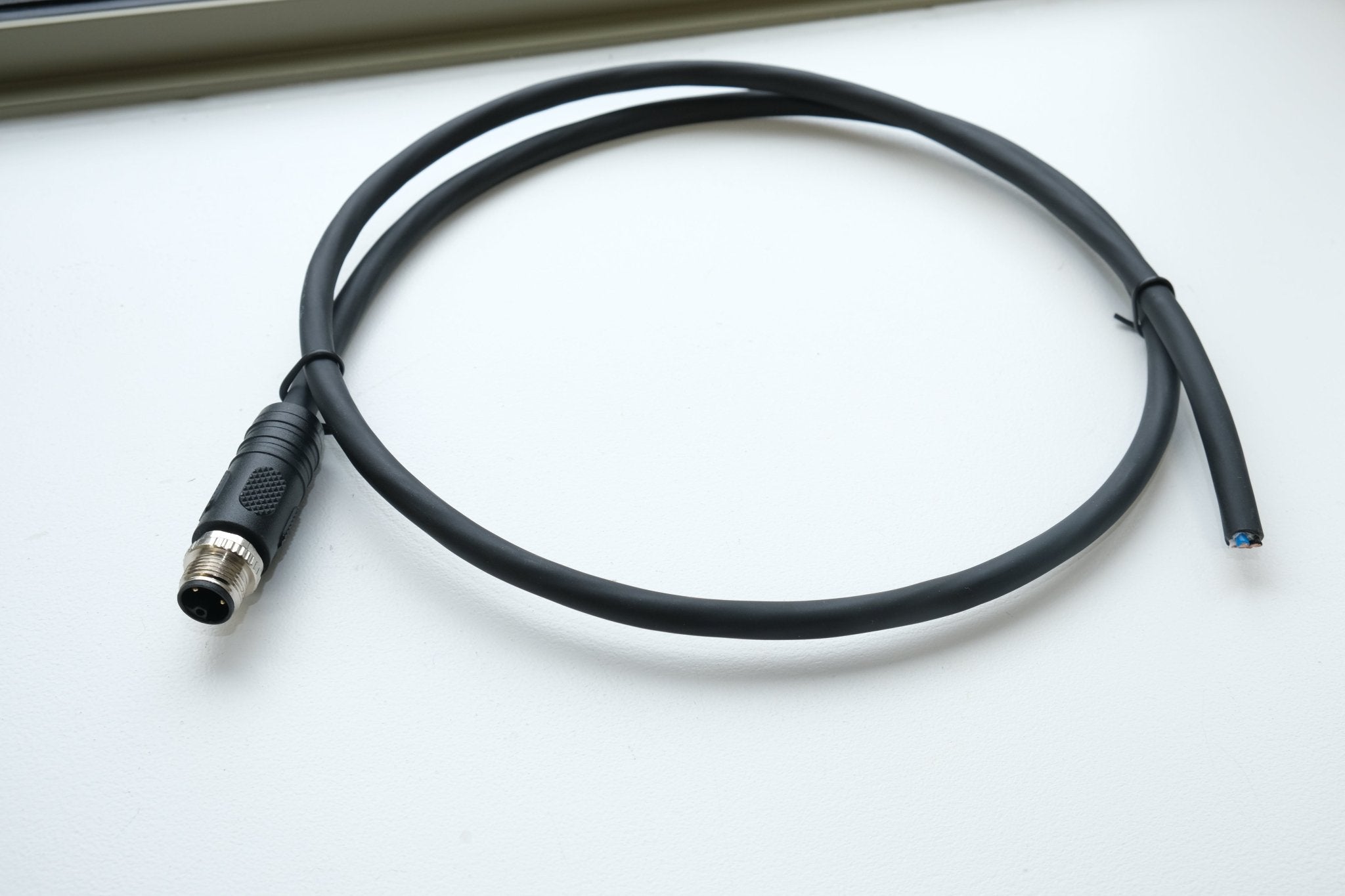 Black cable with a connector on a white surface