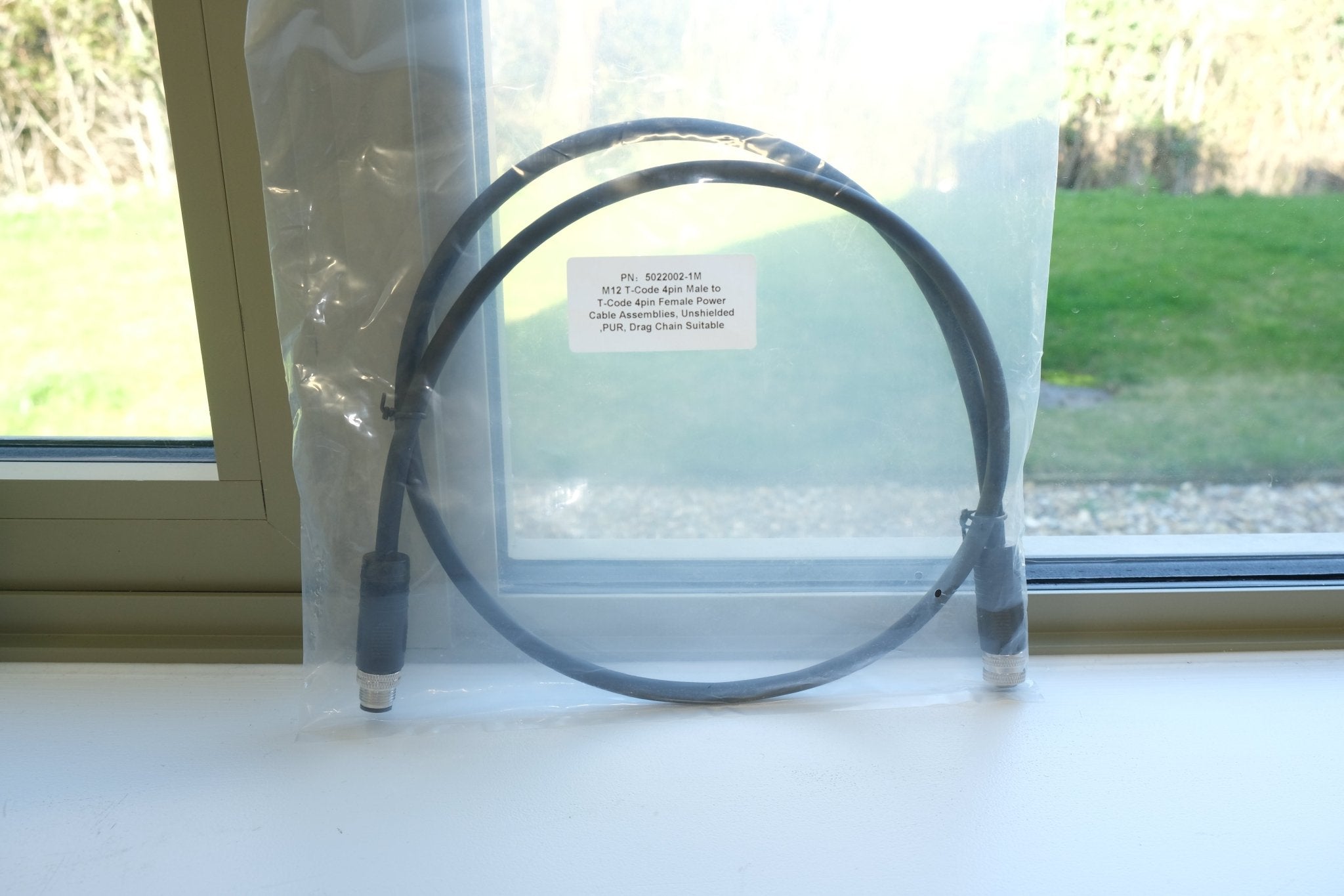 Black cable on a white surface with a window in the background