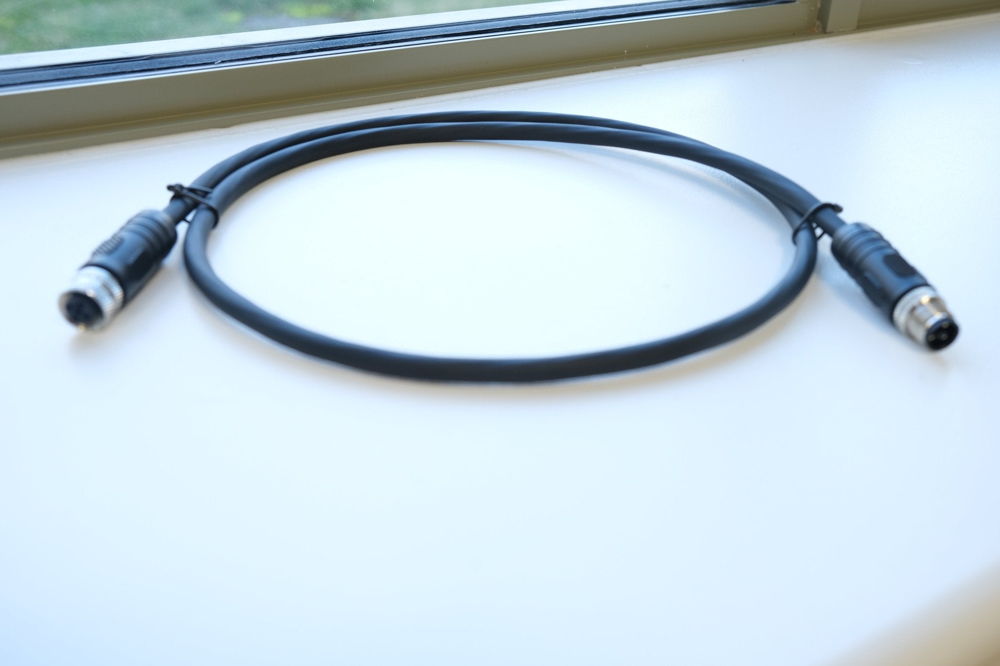 Black cable with connectors on a light surface