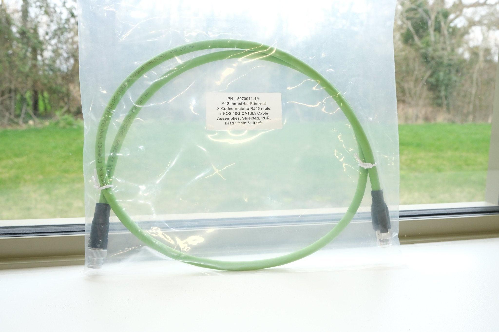 Green cable on a white surface with a window in the background