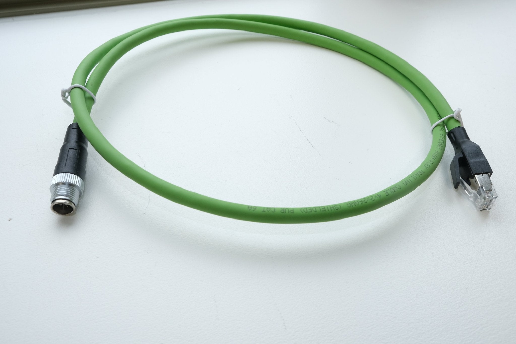 Green cable with one end as an XLR connector and the other as an Ethernet connector on a white background