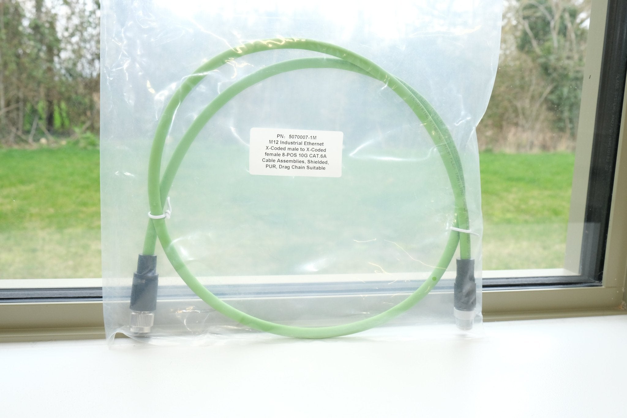 Green hoop on a clear plastic stand with a label, against a window background.