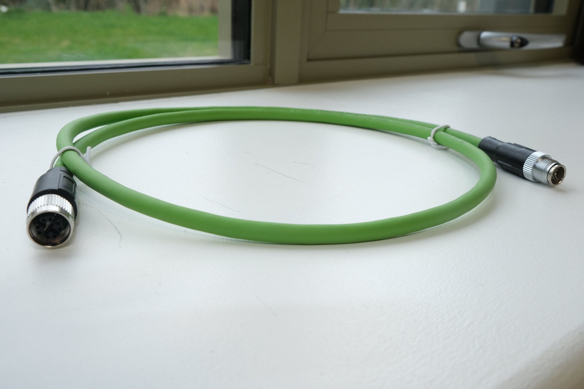 Green cable with XLR connectors on a white surface