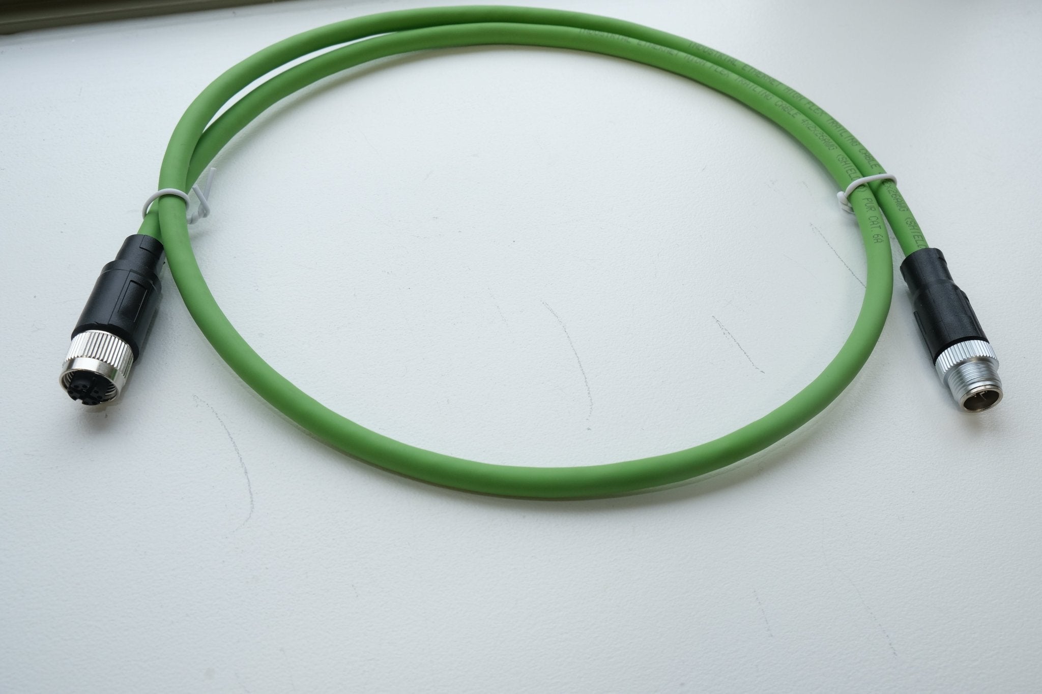 Green cable with black connectors on a white background