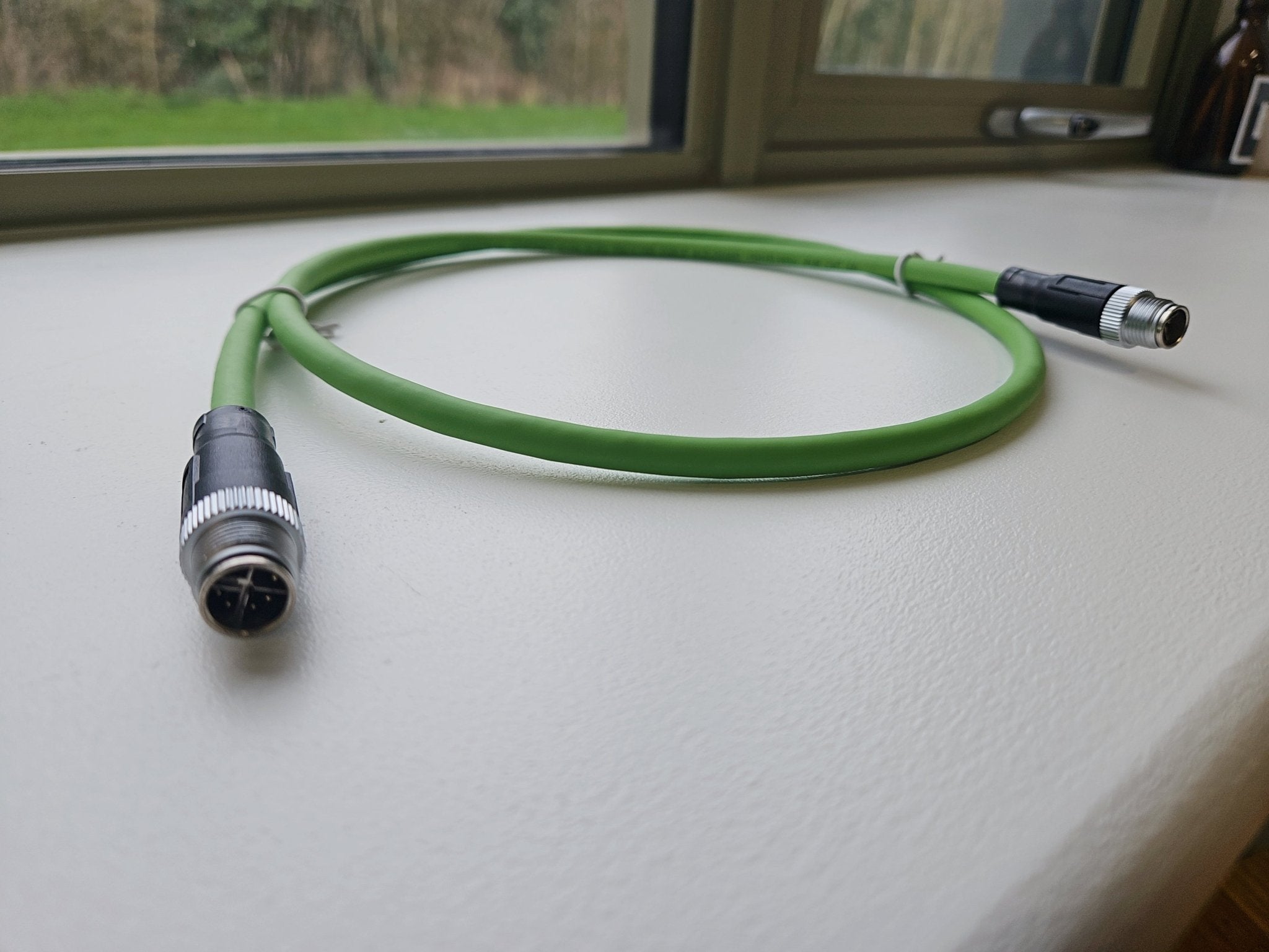 Green cable with black connectors on a white surface